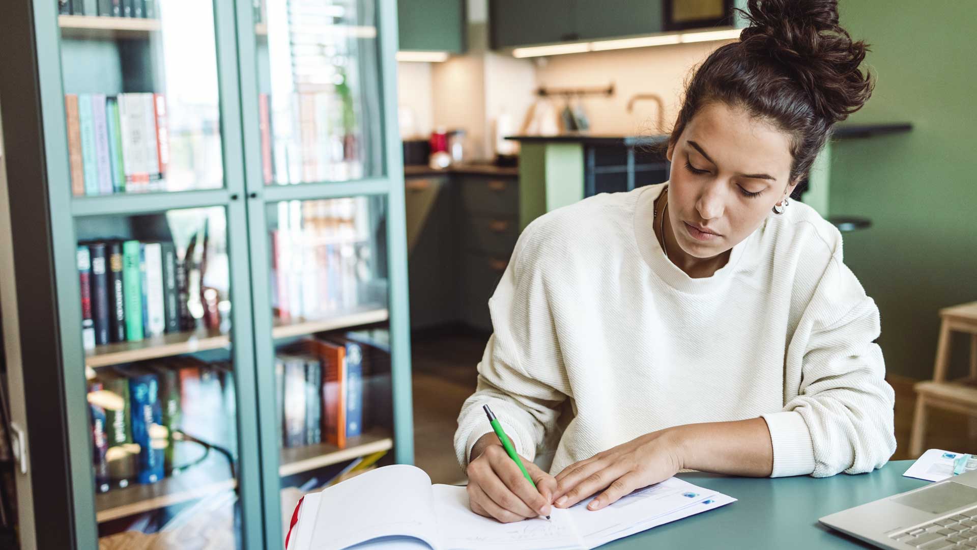 Studentin macht sich Notizen am Schreibtisch