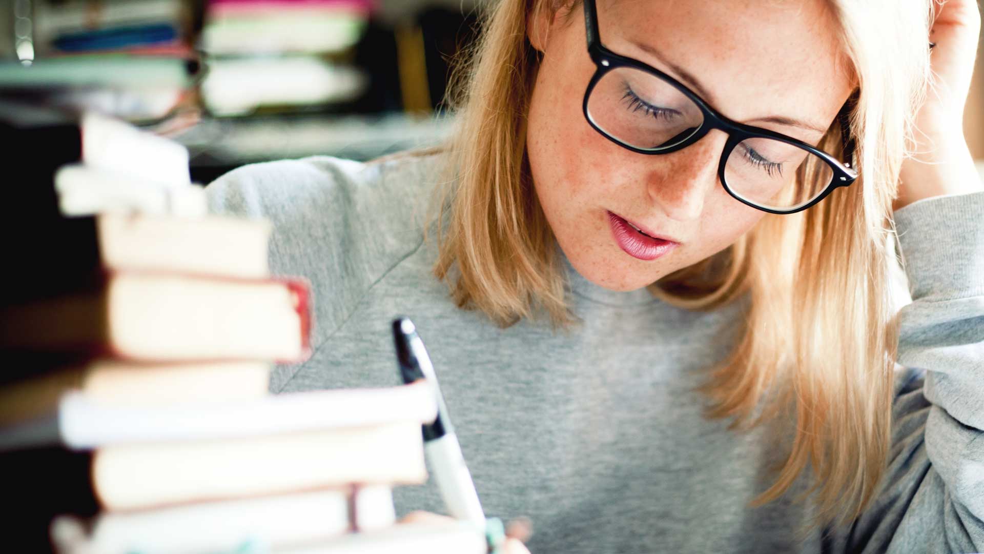 Junge Frau mit Büchern am Schreibtisch