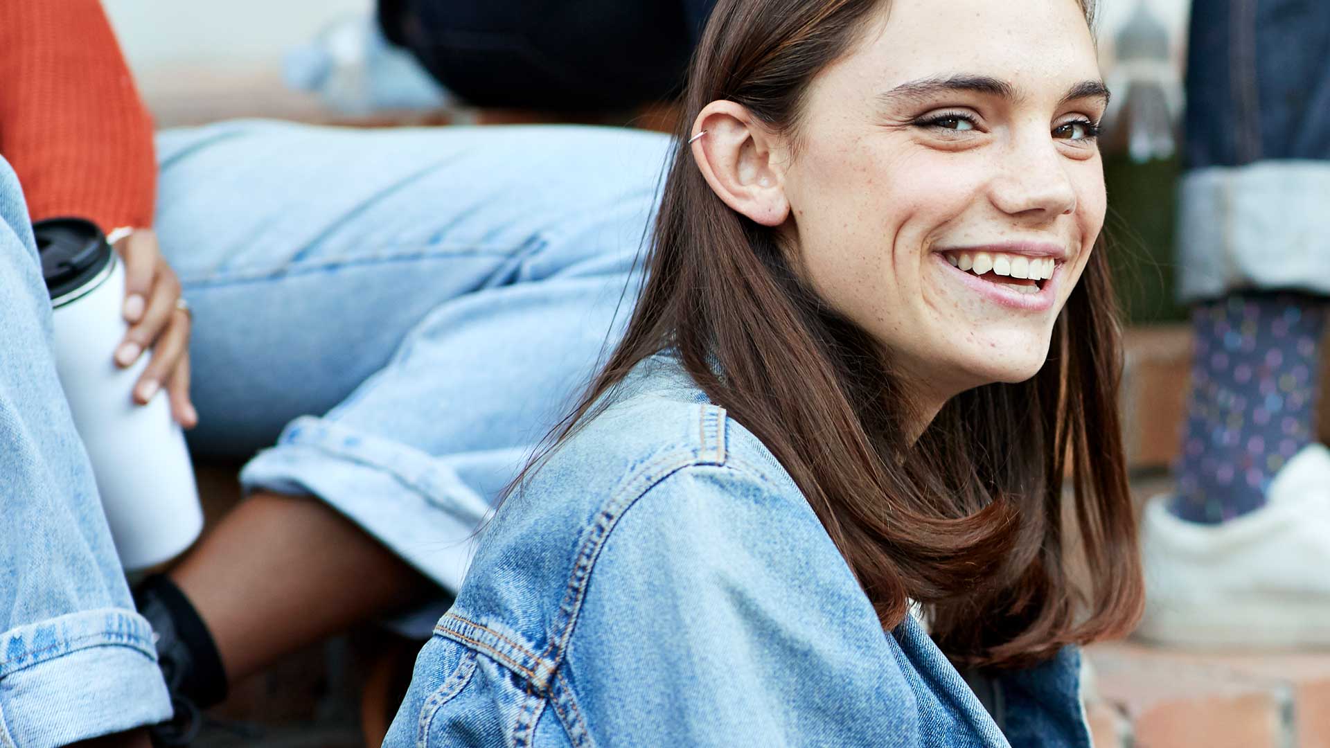 Titelbild zum Artikel "Was machen nach dem Abitur": Abiturientin sitzt mit Freunden draussen