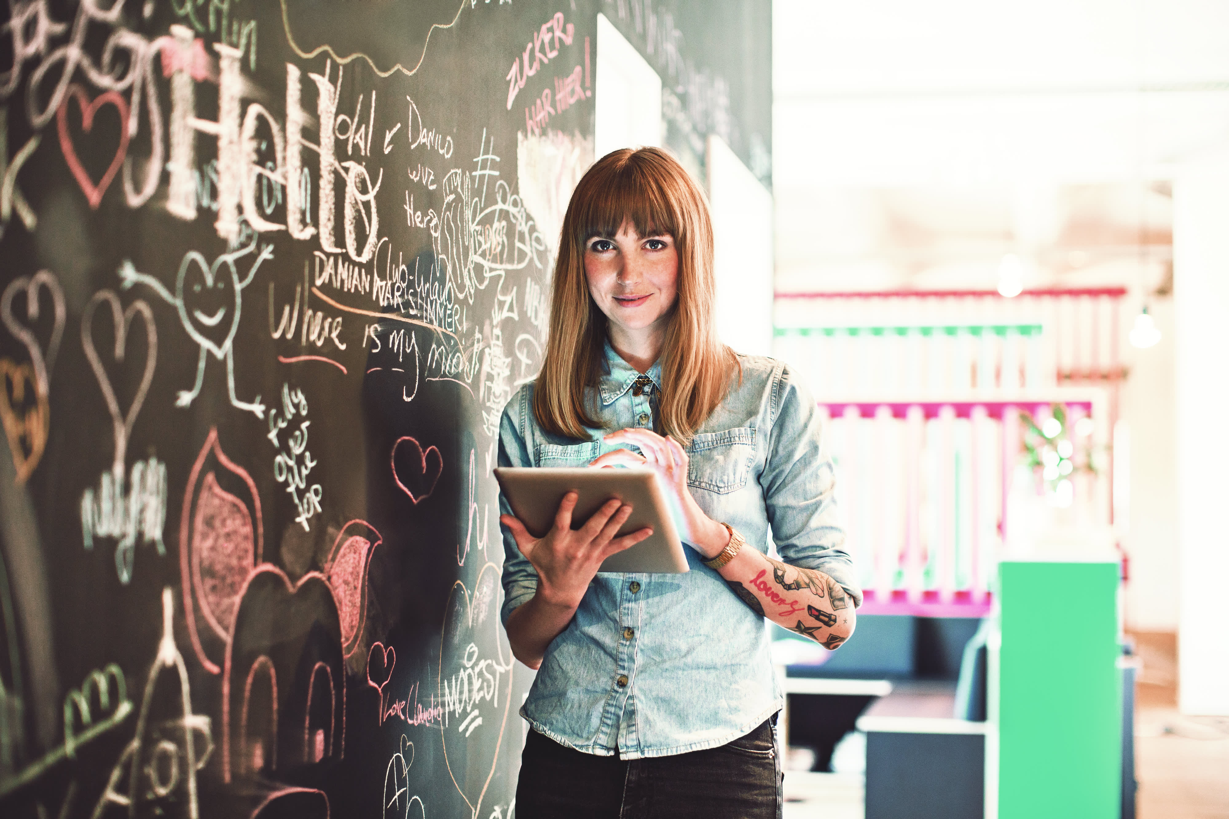 Titelbild für Infoseite “Bachelor Marketingmanagement”: Marketingmanagerin steht mit Tablet vor Whiteboard im Büro