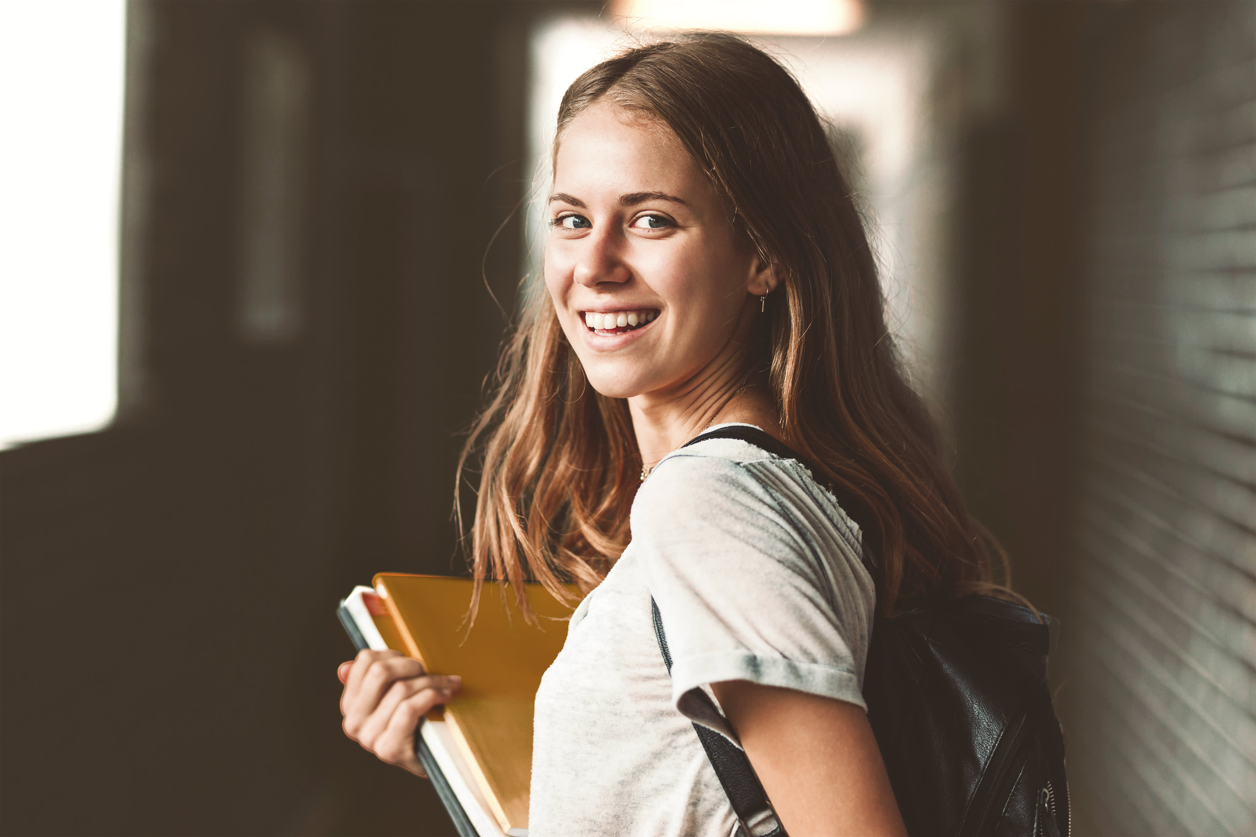 Hintergrund für Titelbild für Infosweite "duales Studium Lehramt": Studentin trägt Bücher und lacht