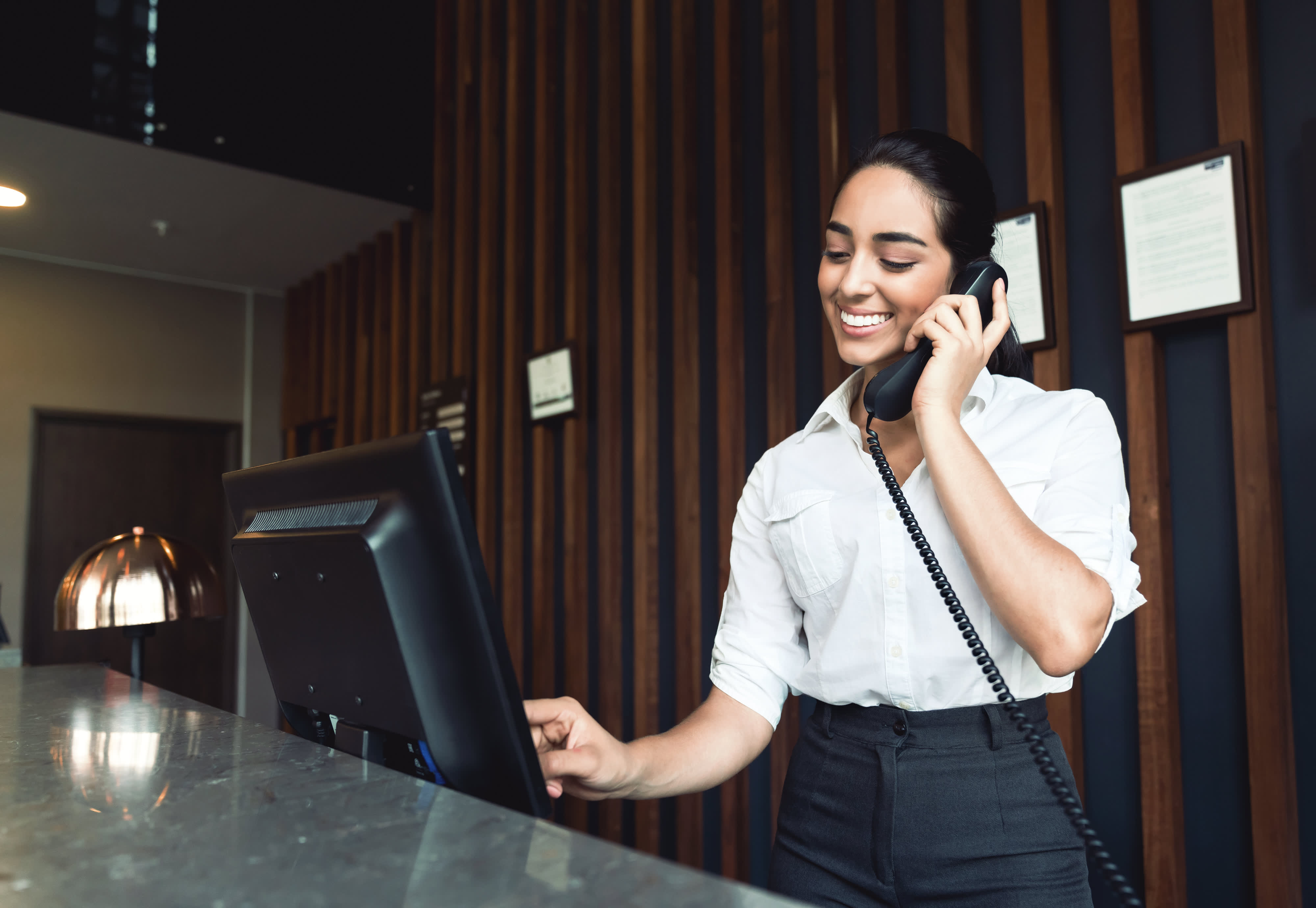 Titelbild für Infoseite “Bachelor Hospitalitymanagement”: Hospitalitymanagerin steht an der Hotelrezeption