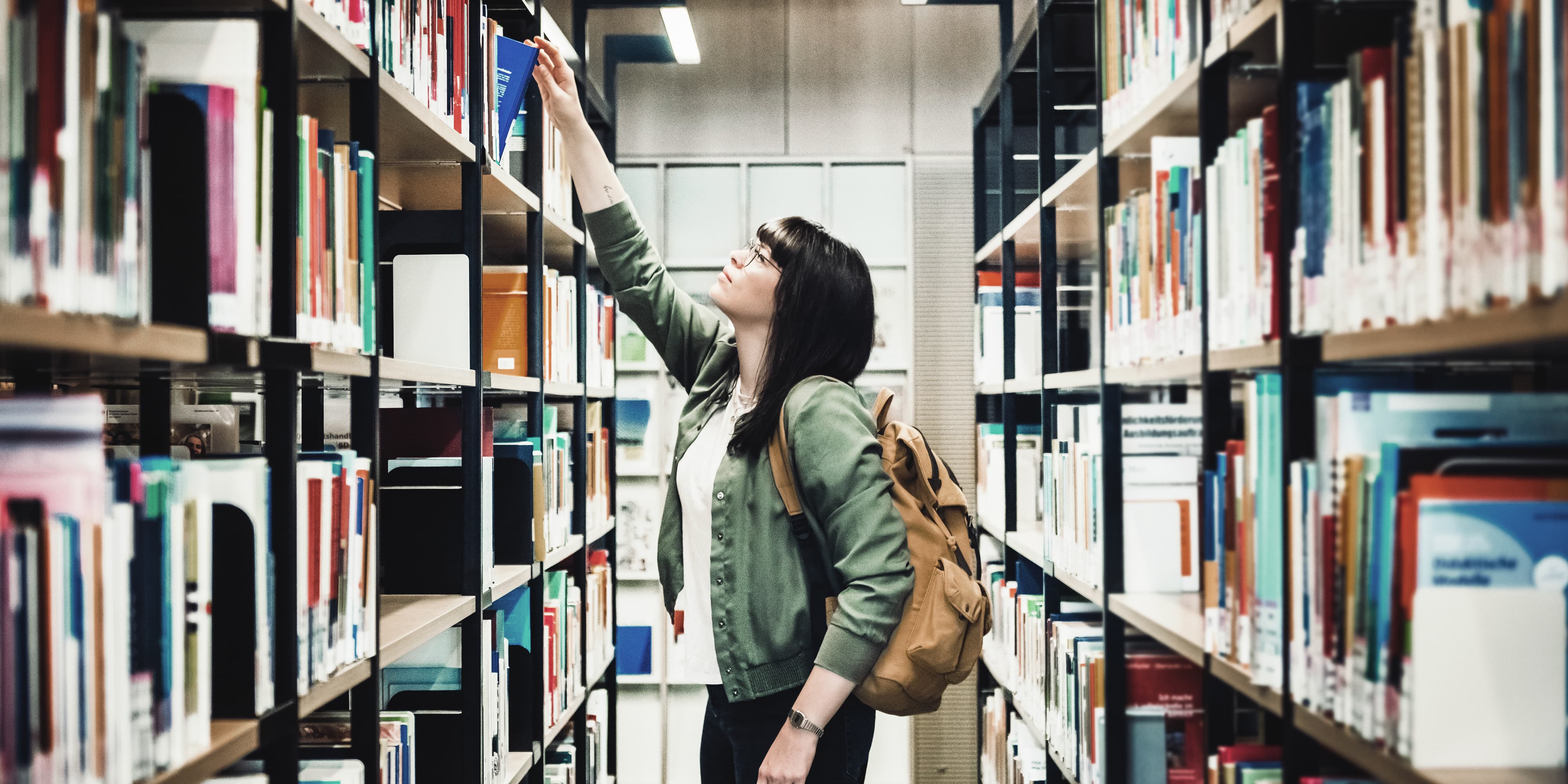Titelbild für Infoseite “Studieren ohne Abitur”: Studentin steht in Bibliothek