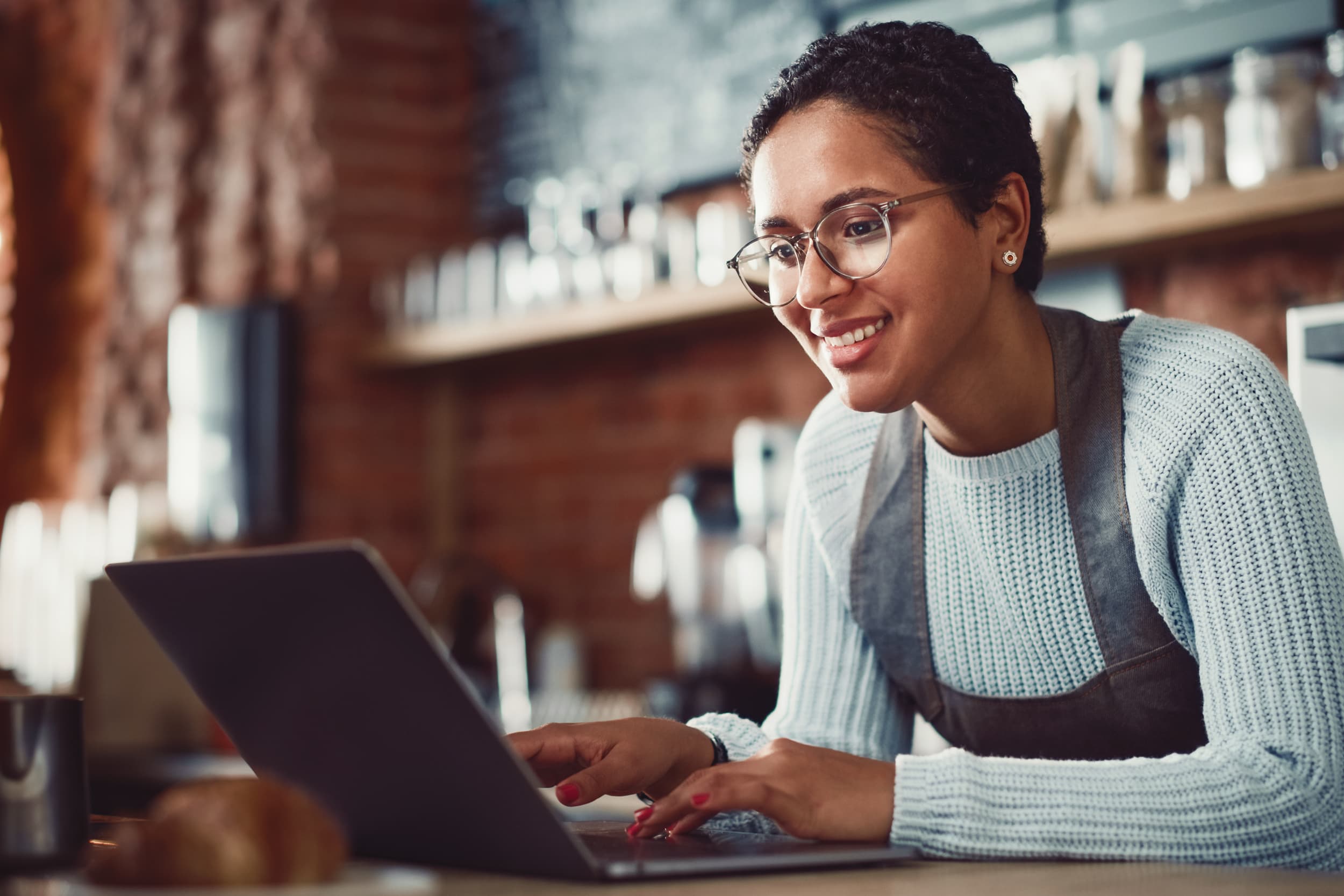 Titelbild für Infoseite: "duales Studium Tourismus und Hospitality": Frau in Gastronomie am Laptop