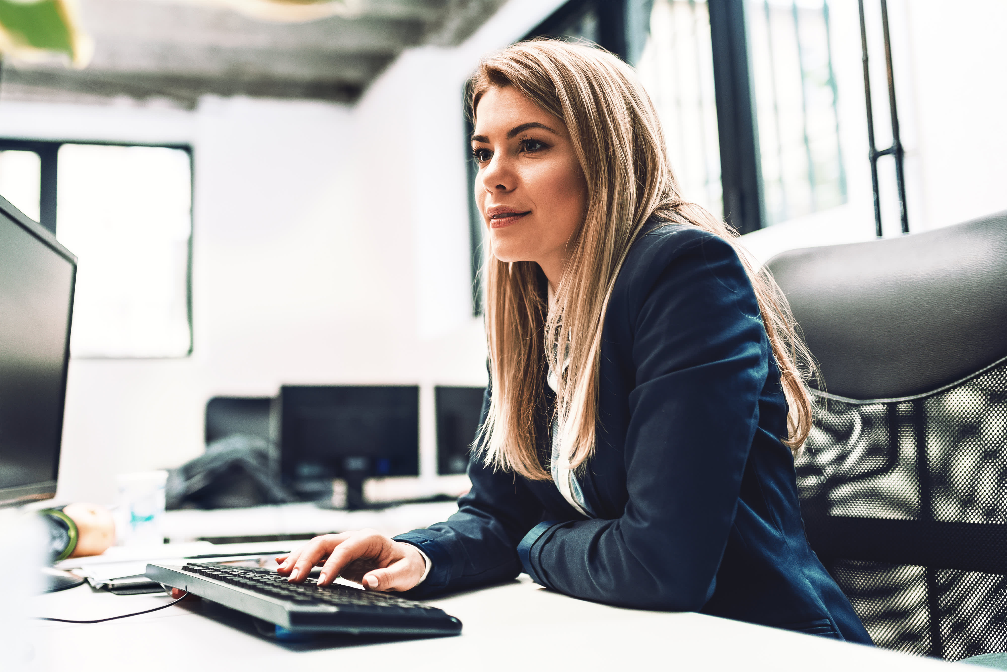 Titelbild für Infoseite “MBA - Salesforce”: Vertriebsleiterin arbeitet am Schreibtisch im Büro