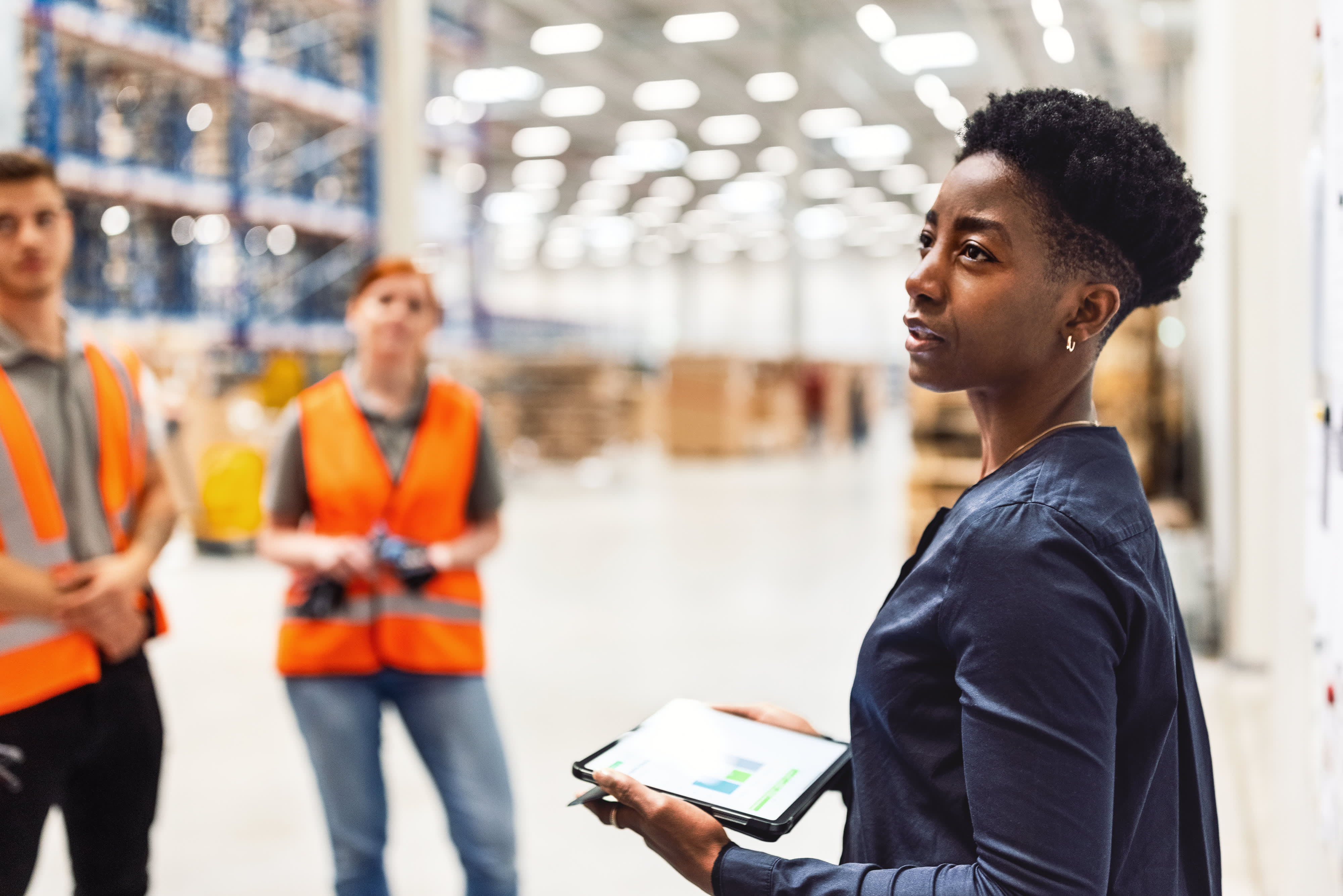 Titelbild für Infoseite “Master Digitale Transformation - Logistik”: Beraterin mit Tablet in Logistikhalle mit Mitarbeitern