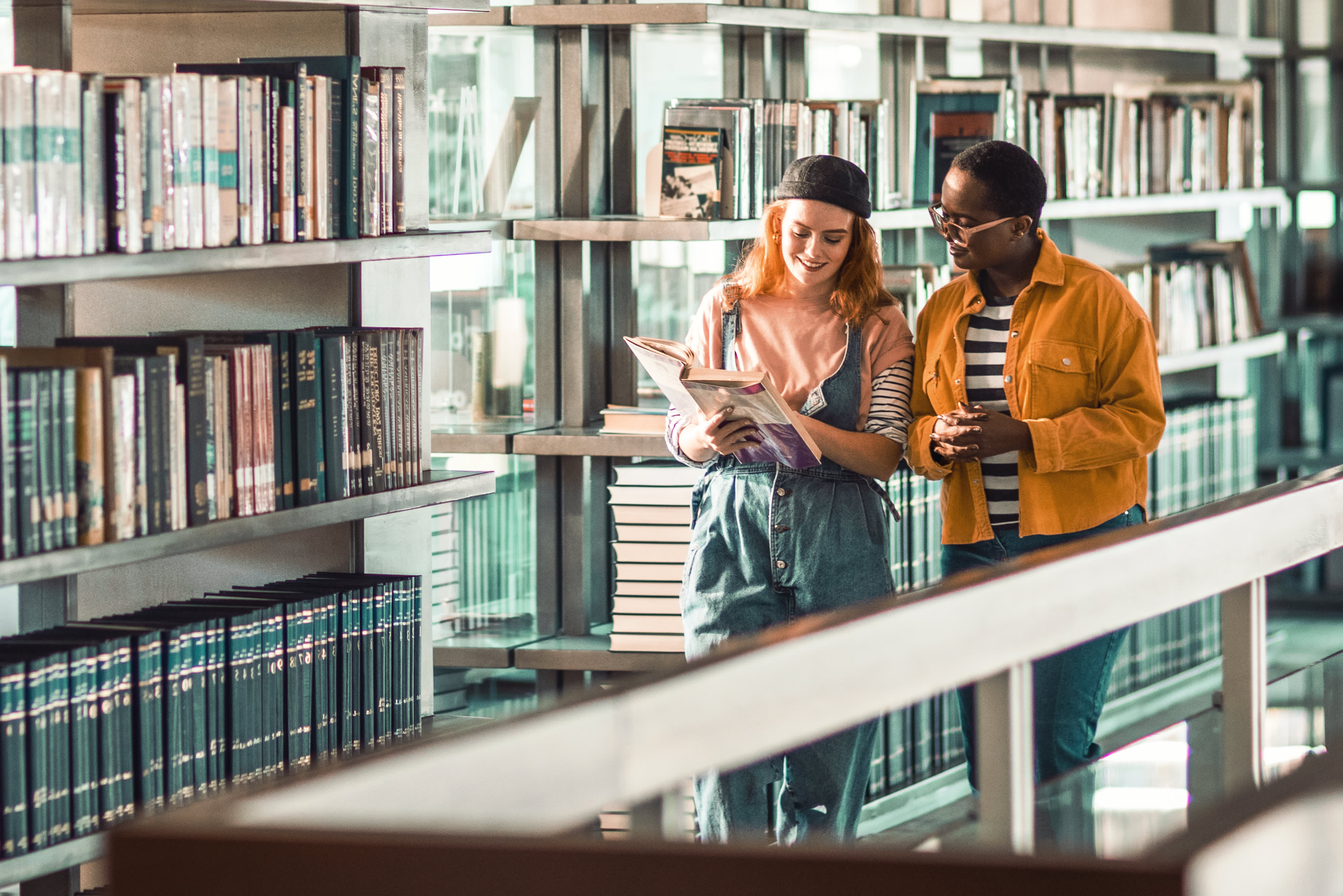 Titelbild zur Infoseite "Publikationen": Studentinnen unterhalten sich in Bibliothek