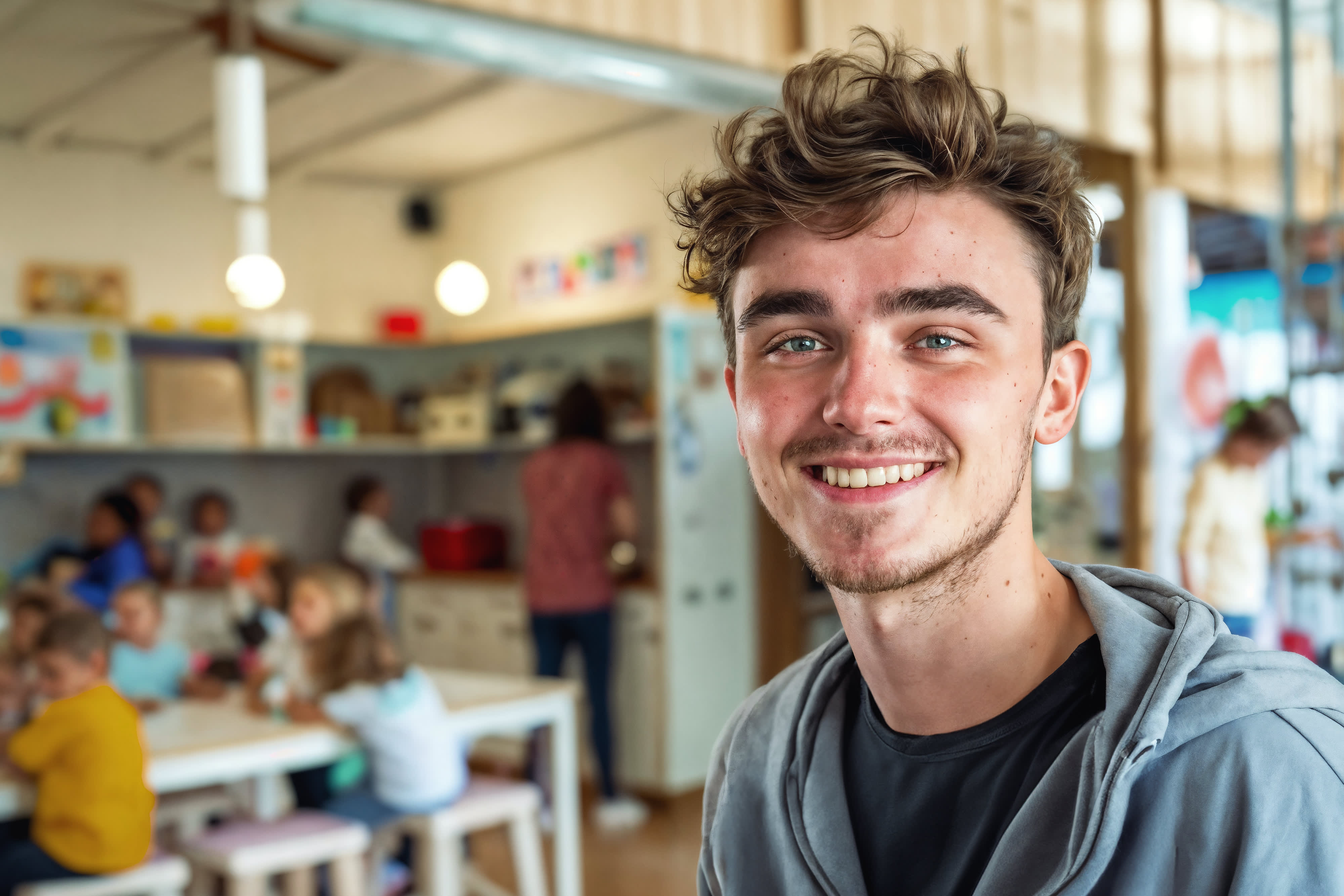 Titelbild der Infoseite "Erzieher Ausbildung Bayern": Junger Mann mit grauem Sweatshir
