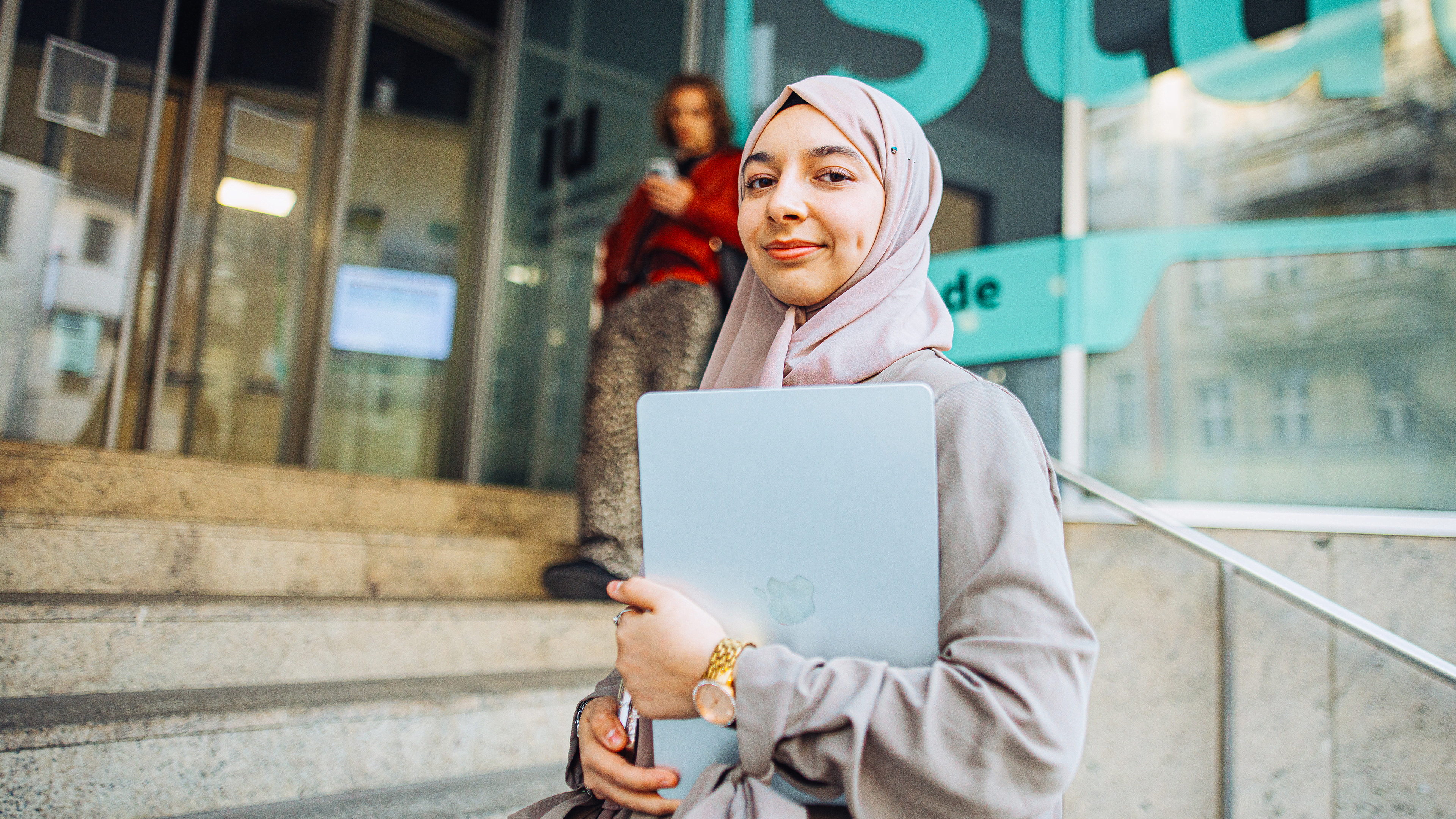 IU student smiling and holding a laptop in her hands