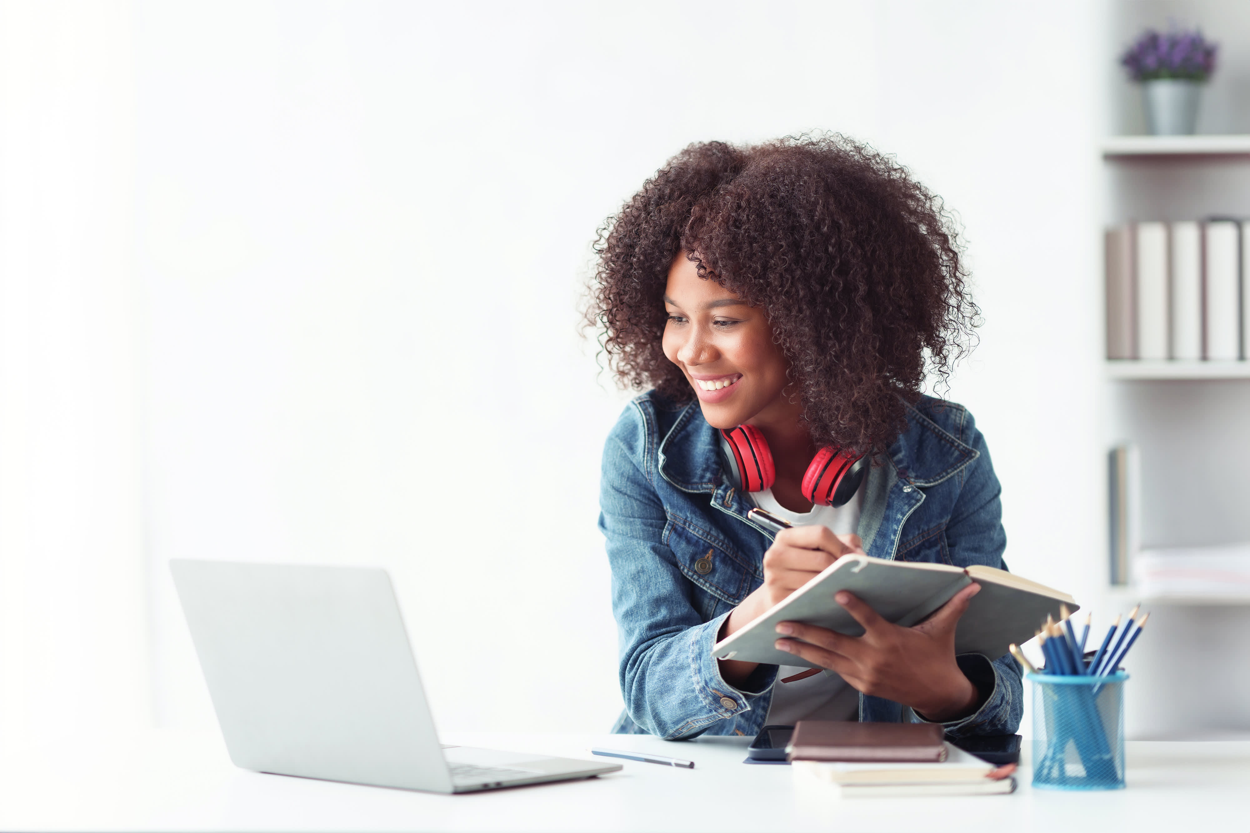 Titelbild der Infoseite "Ausbildung oder Studium": Schülerin sitzt am Schreibtisch, hat einen Laptop vor sich und macht sich Notizen über eine Ausbildung und ein Studium