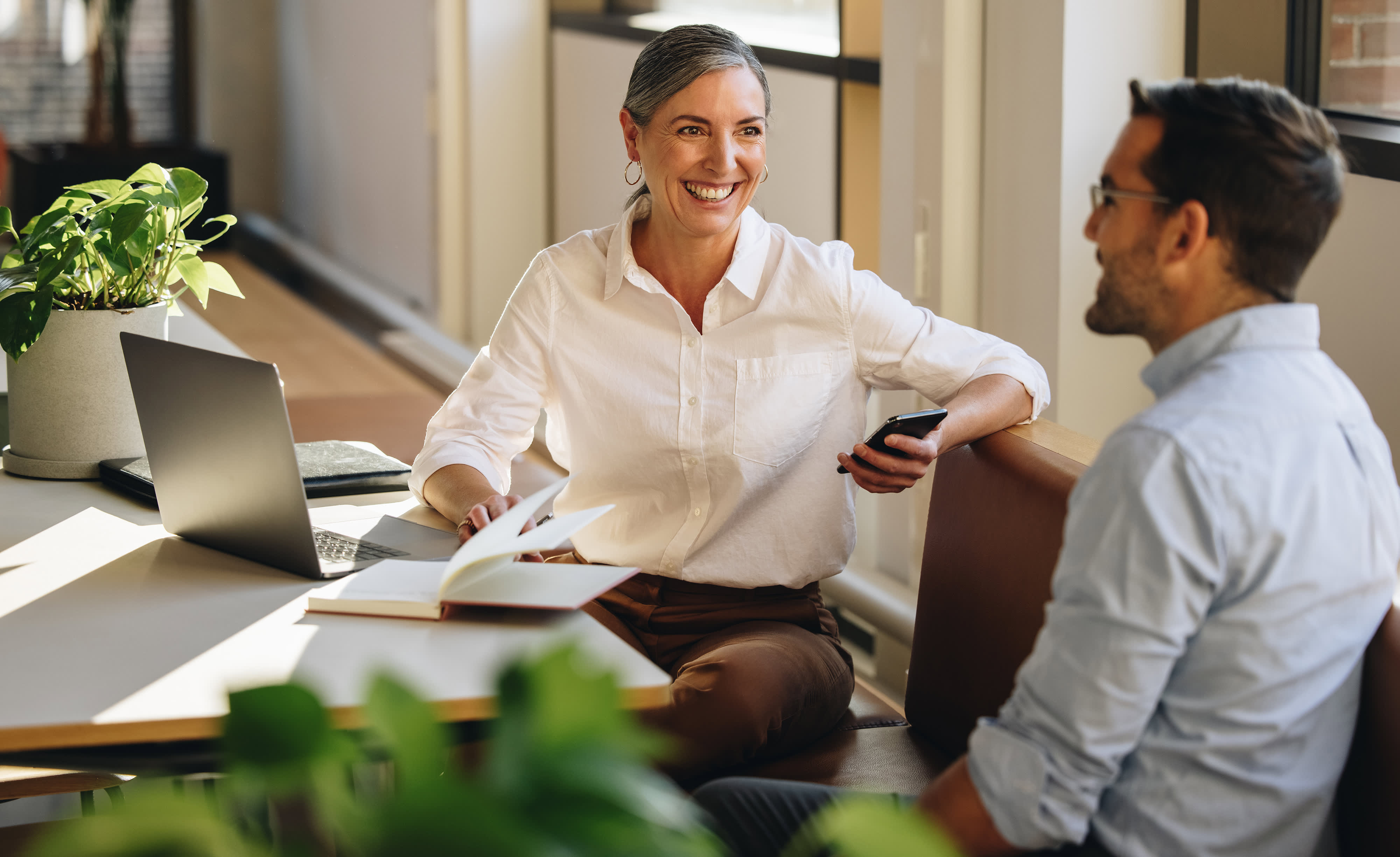 A woman and a man are sitting in an office with a laptop