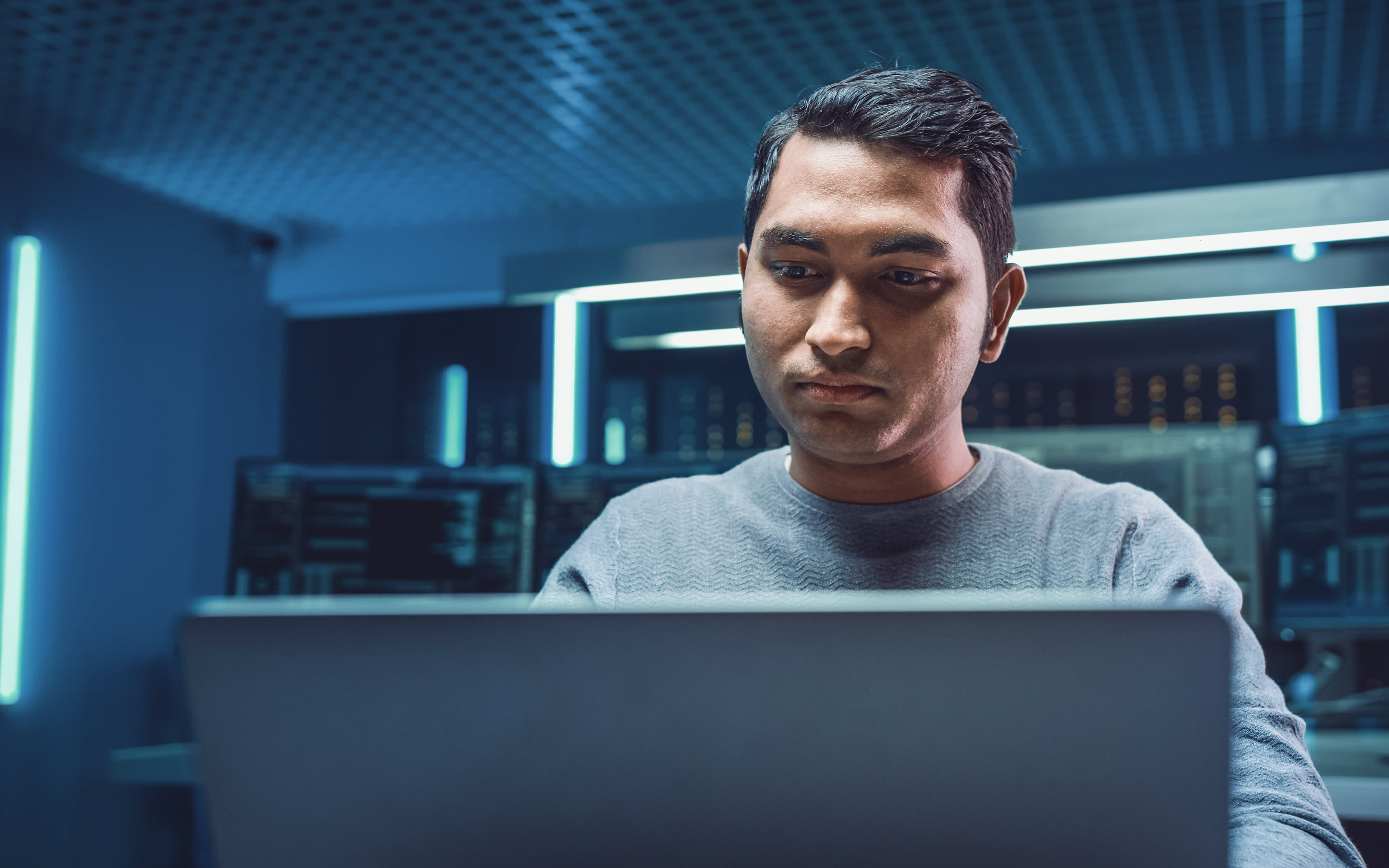 A person in a high-tech computer lab works intently on a laptop, illustrating a modern environment for participating in a Data Science program.