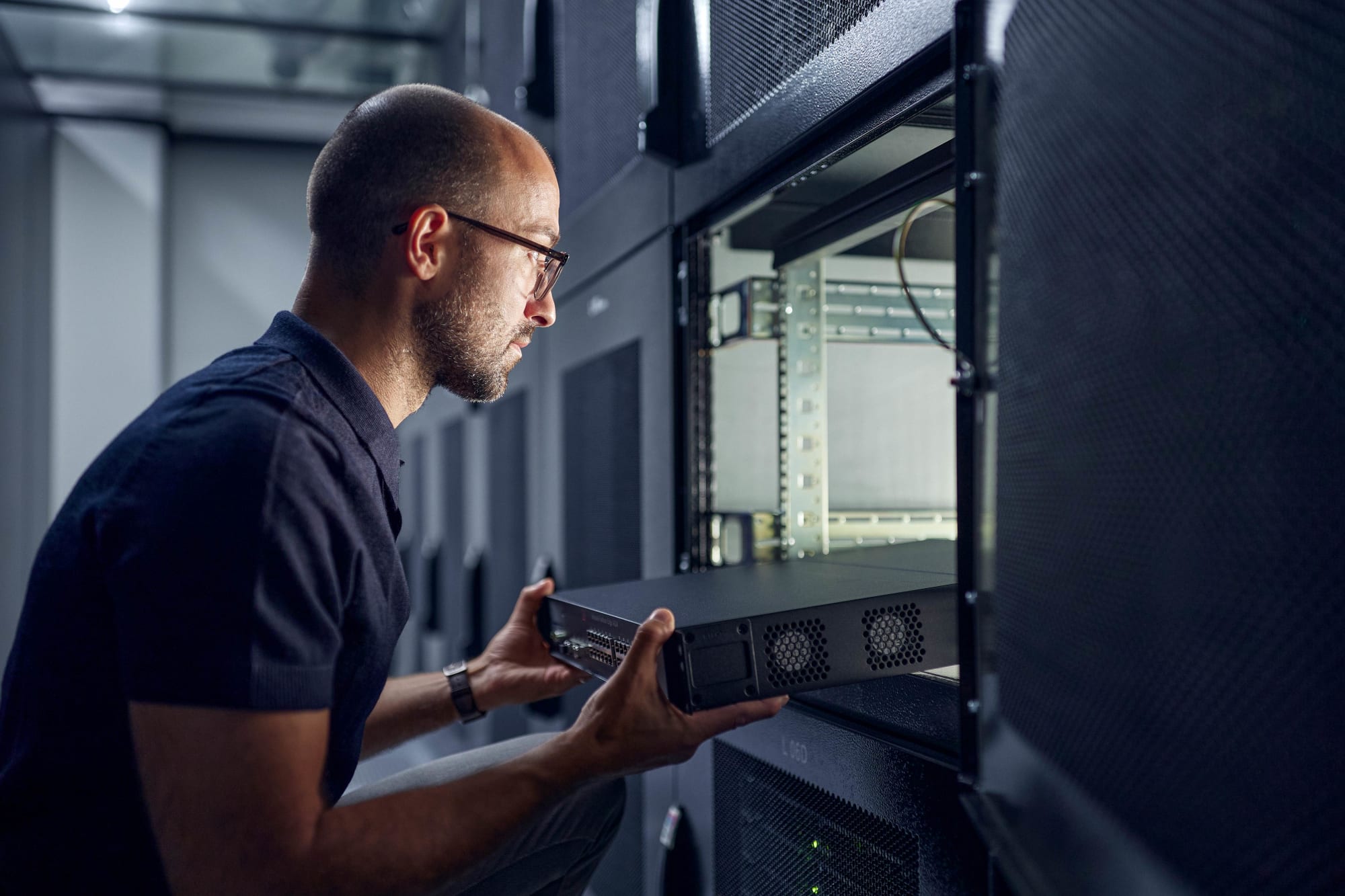 Mann schiebt Server mit beiden Haenden in ein Viertelrack