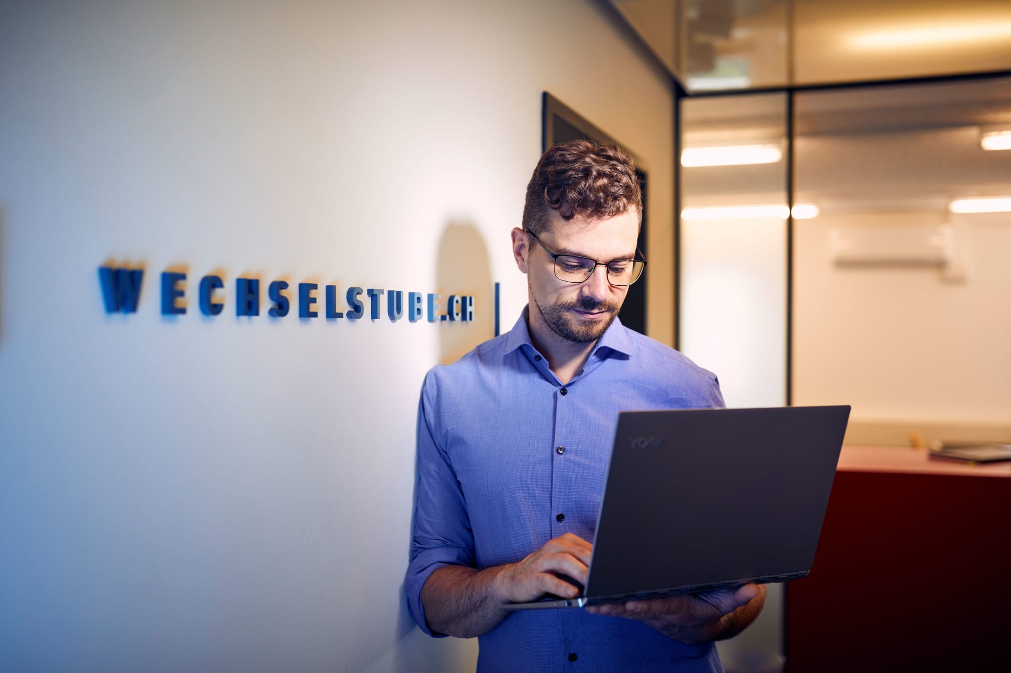 Mann stehend im Unternehmen schaut auf seinen Laptop