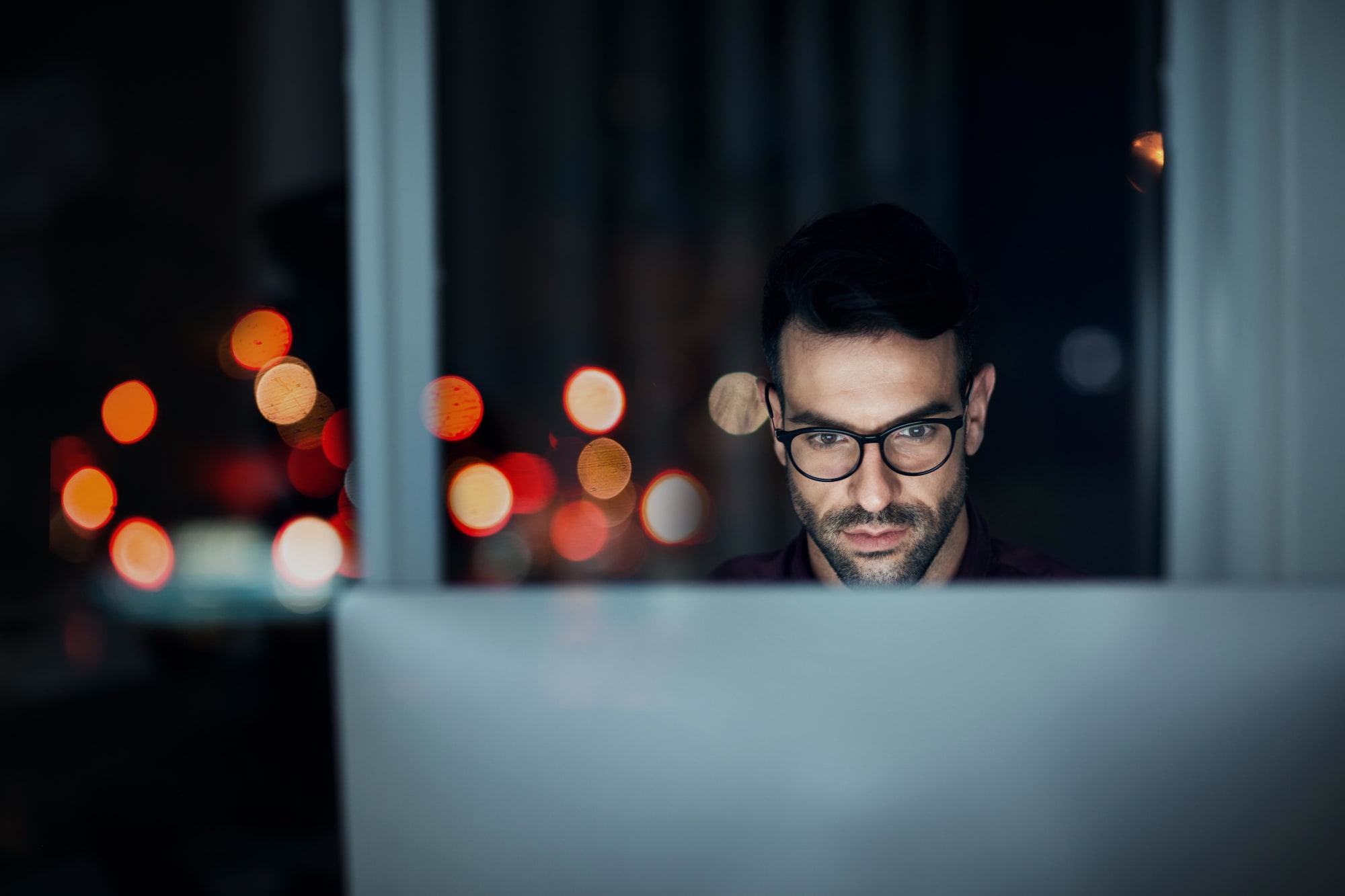 Mann arbeitet nachts fokussiert am PC