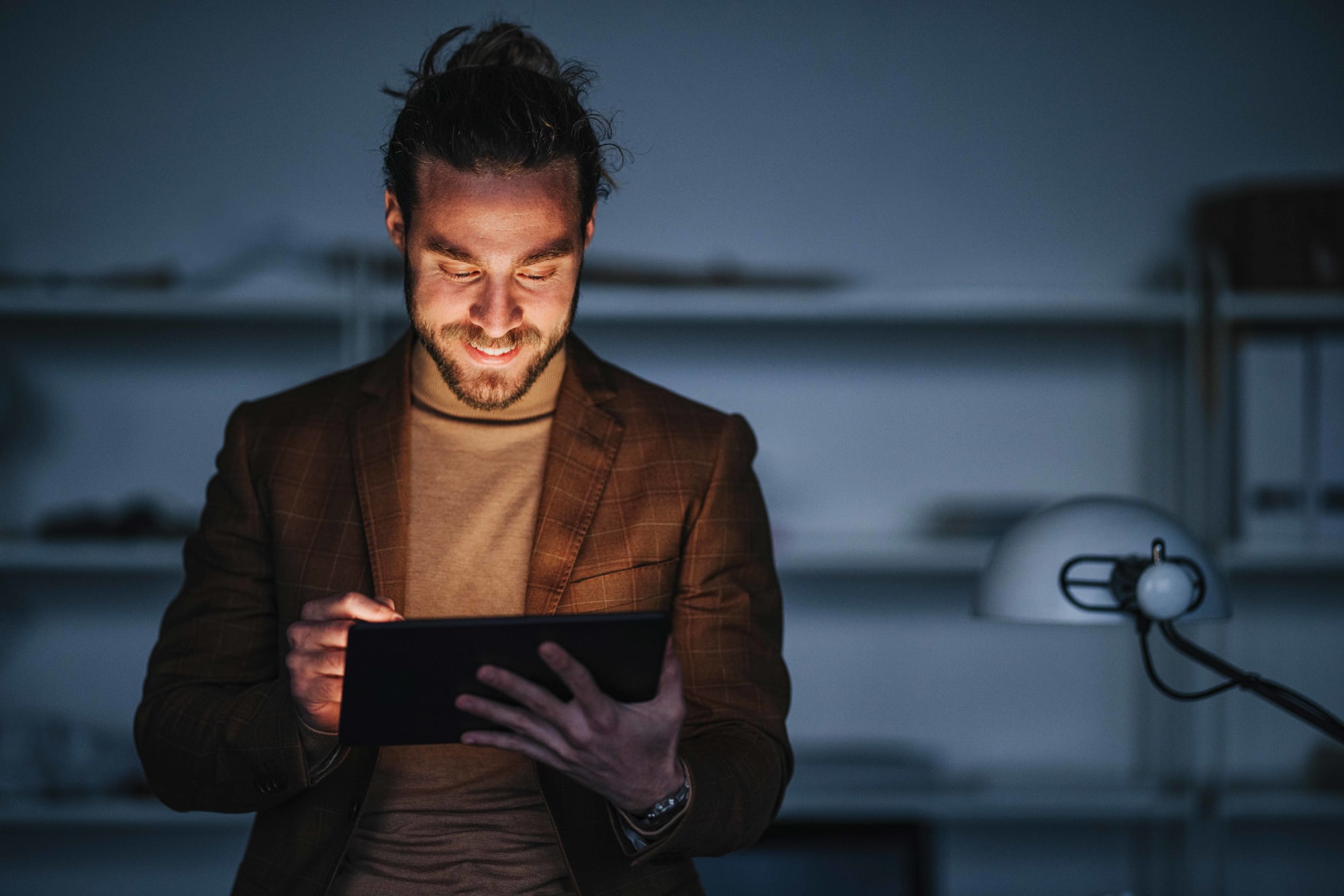 Mann liest etwas auf Tablet und wird vom Licht angestrahlt