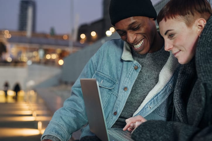 Junges Paar sitzt gemeinsam am Laptop und surft im Internet