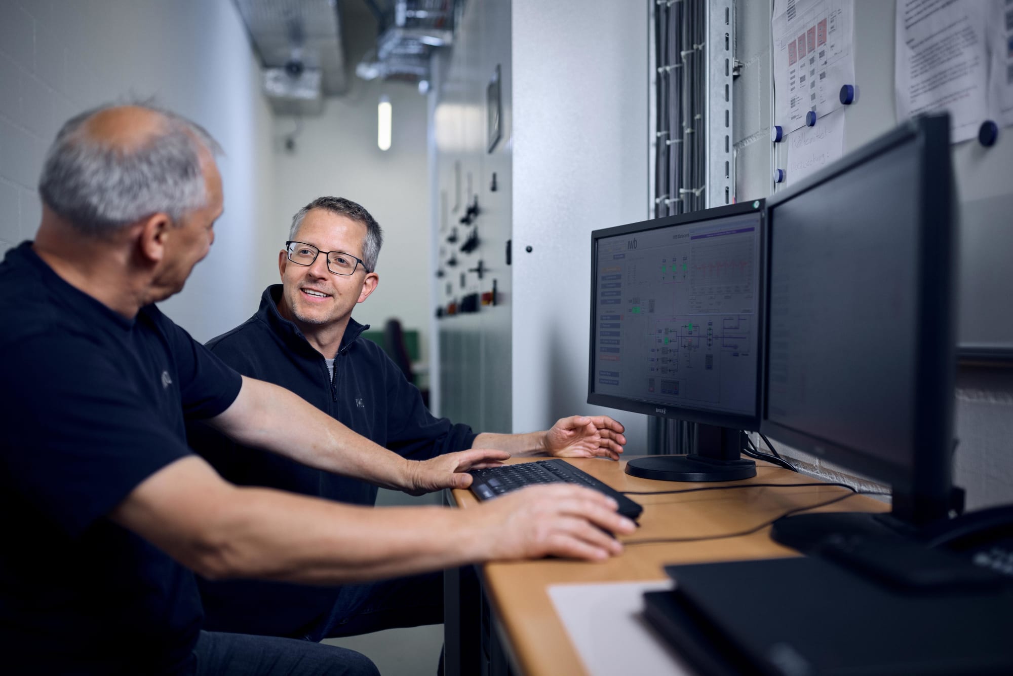 Zwei IWB Mitarbeitende sitzen am PC und besprechensich