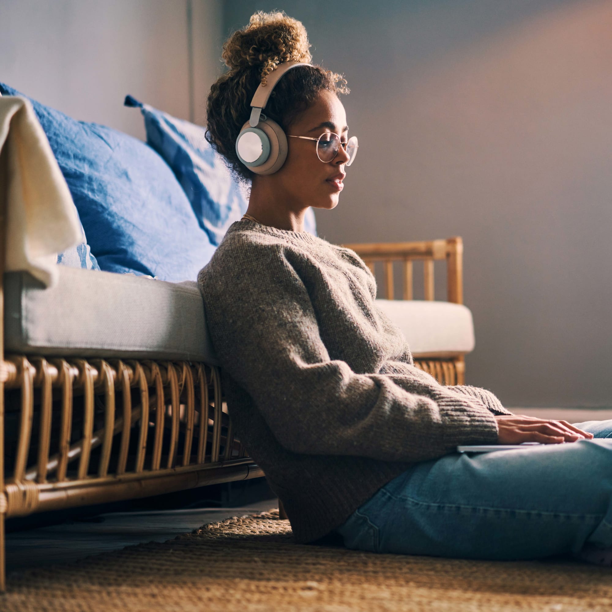 Frau sitzt vor Couch am Laptop und streamt einen Film
