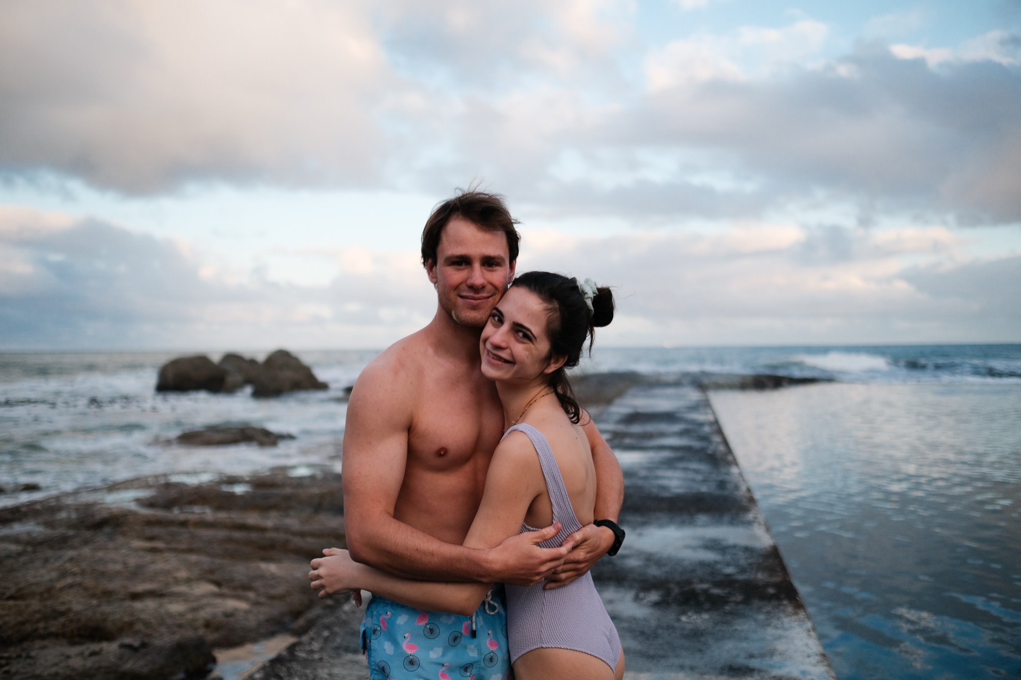 Tristan and Erin embracing by the sea at dusk