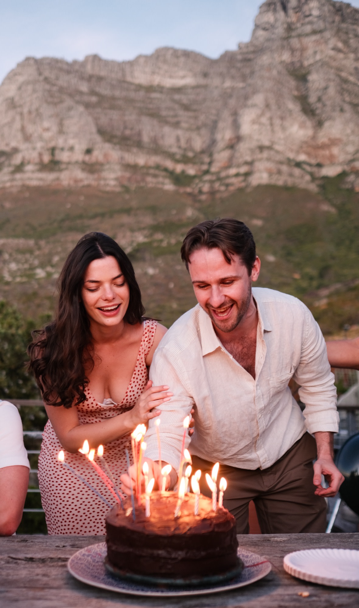 Friends gathered around the candlelit cake