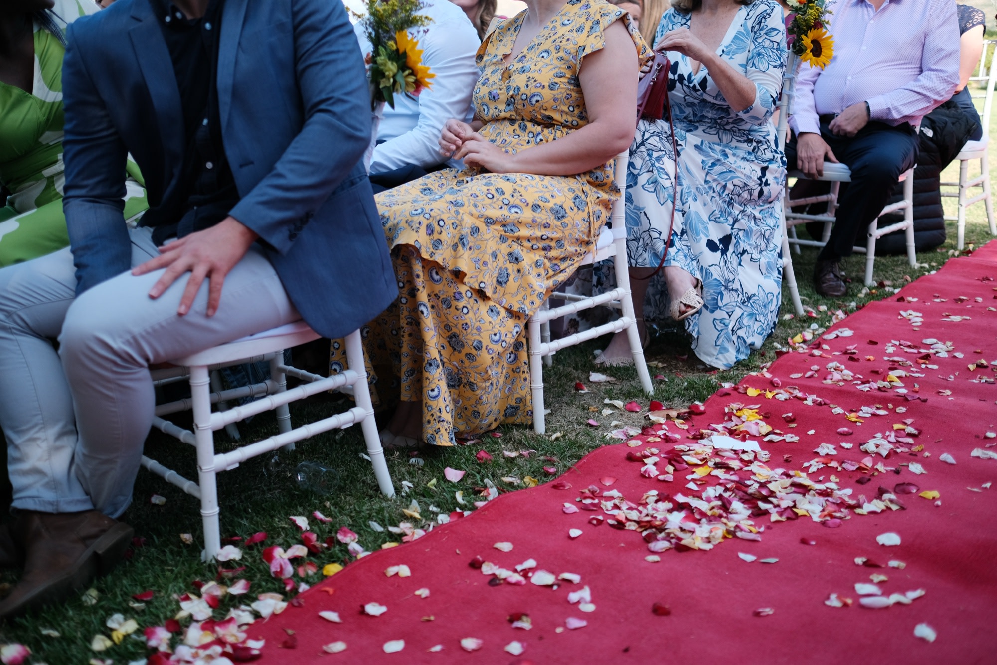Guests seated along the rose-petal-strewn red aisle