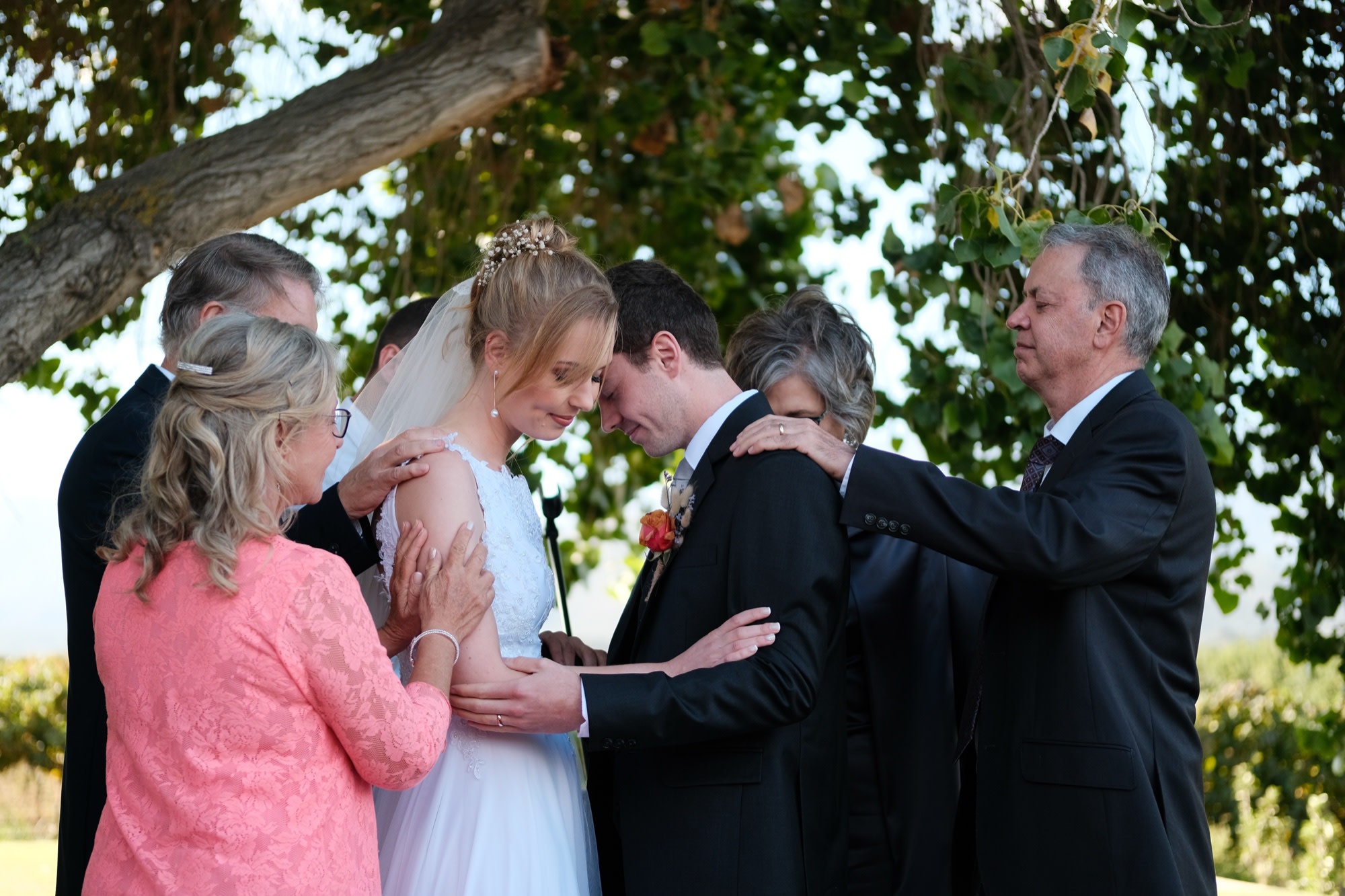 Both families lay hands on the couple in a blessing during the ceremony