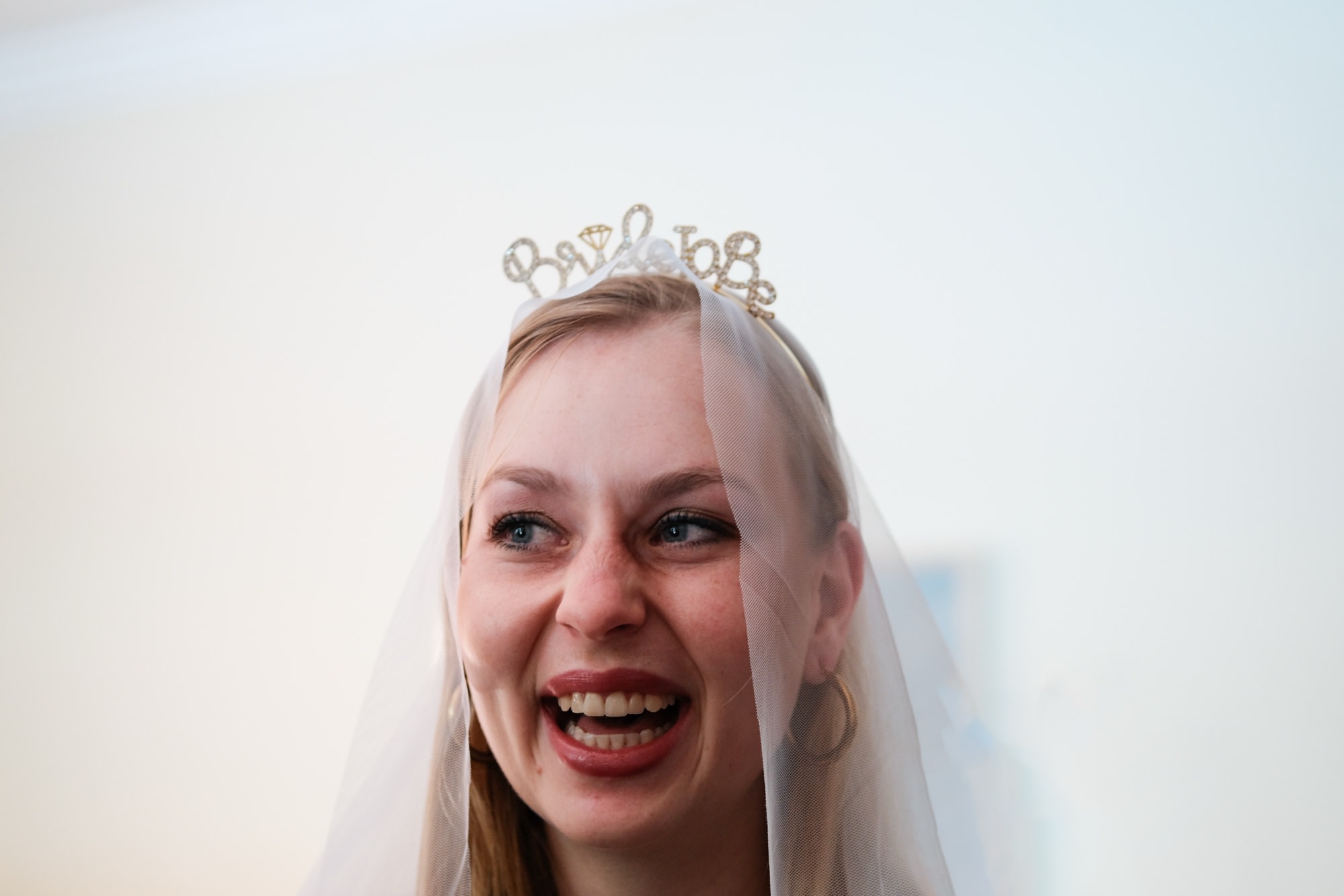 The bride laughing in her veil and 'Bride to Be' tiara