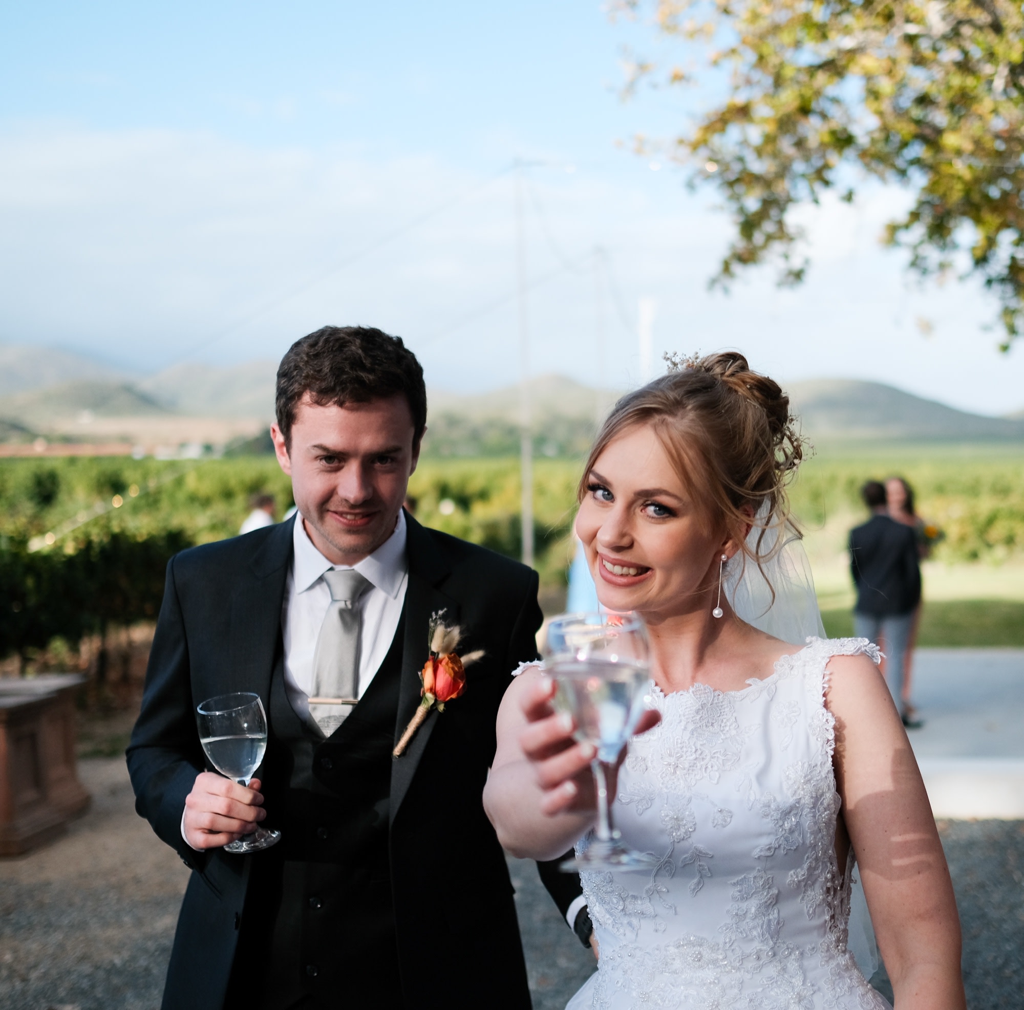 The bride and groom raise a champagne toast in the vineyard