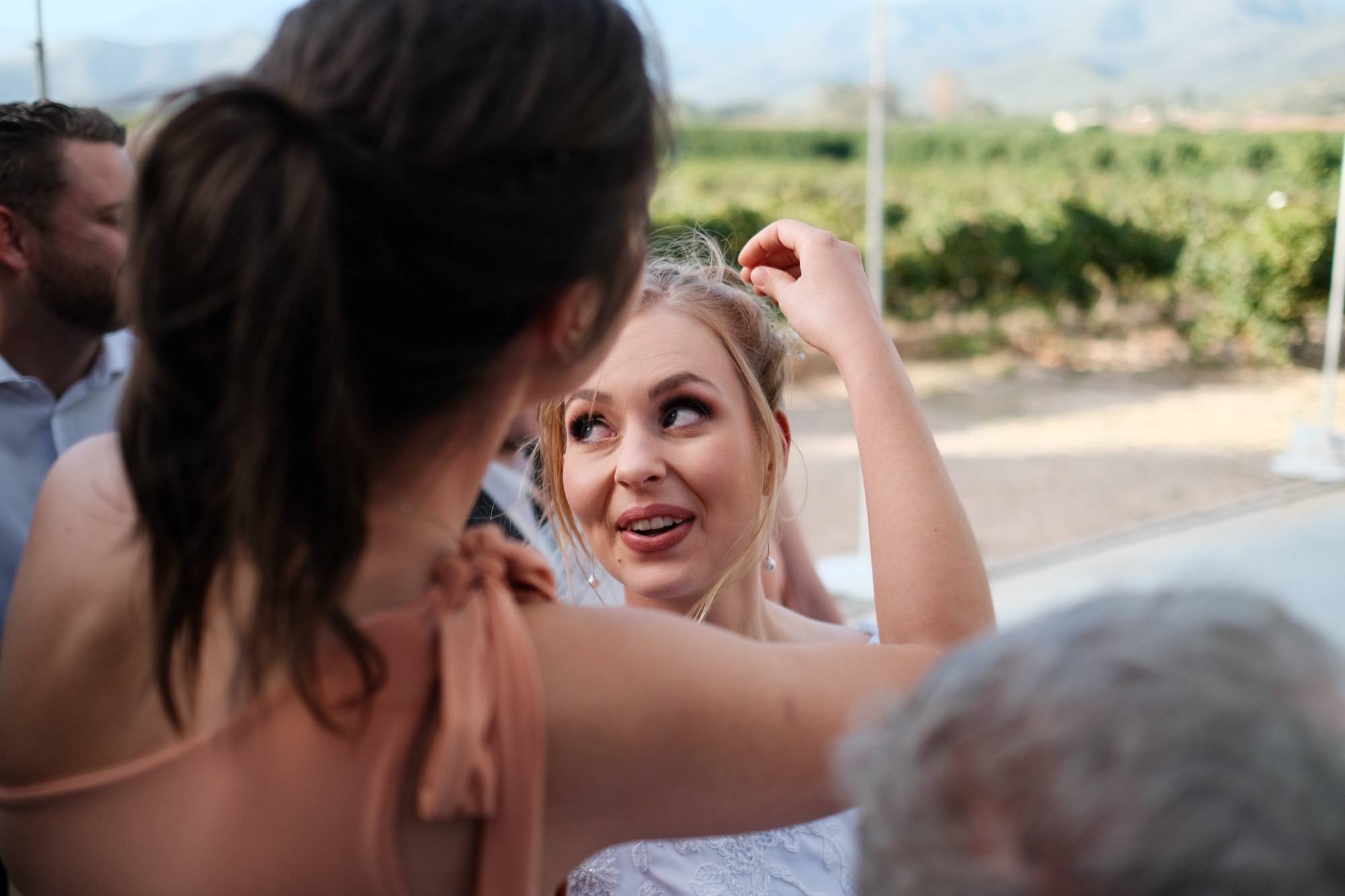 A bridesmaid fixing the bride's hair, a quiet candid moment