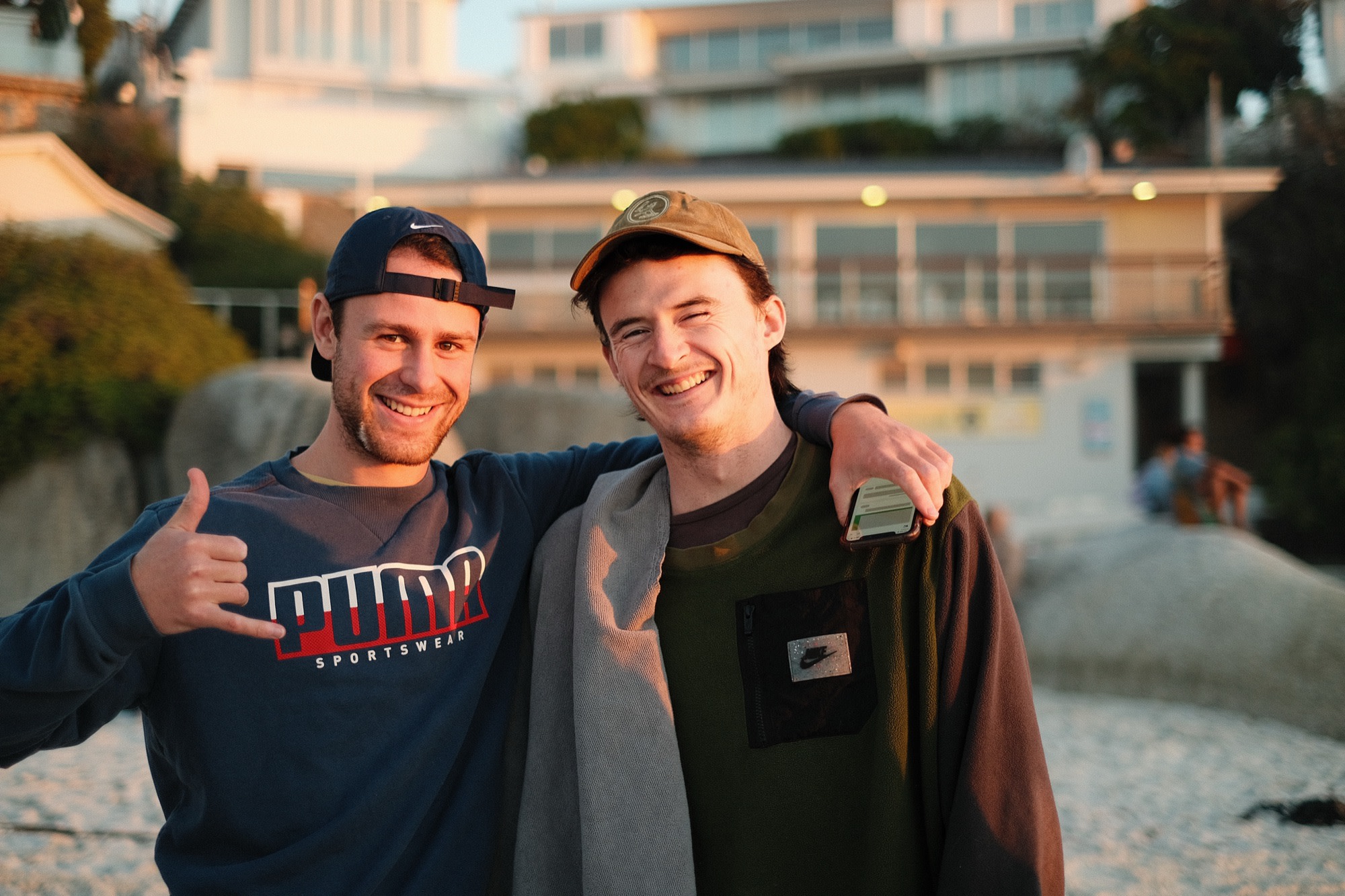 Two friends arm in arm at a beach sunset