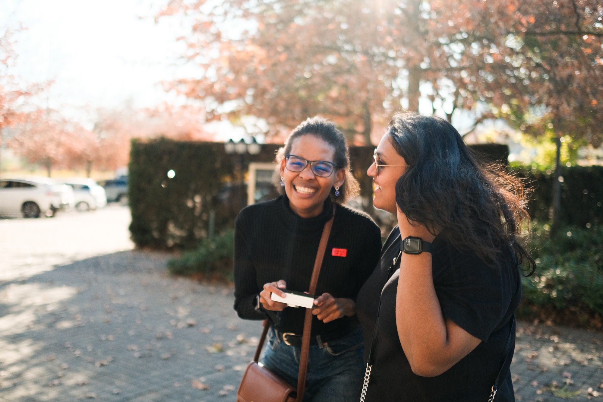 Two friends laughing together under autumn trees