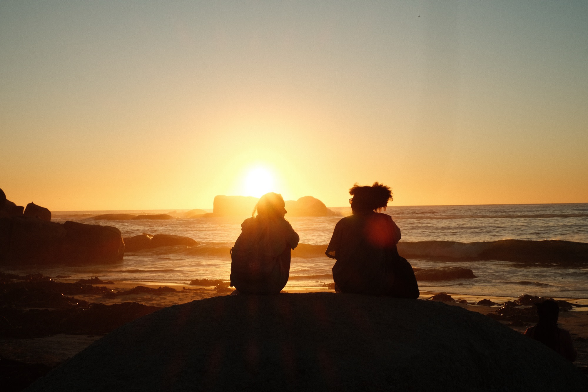 Friends silhouetted against a beach sunset