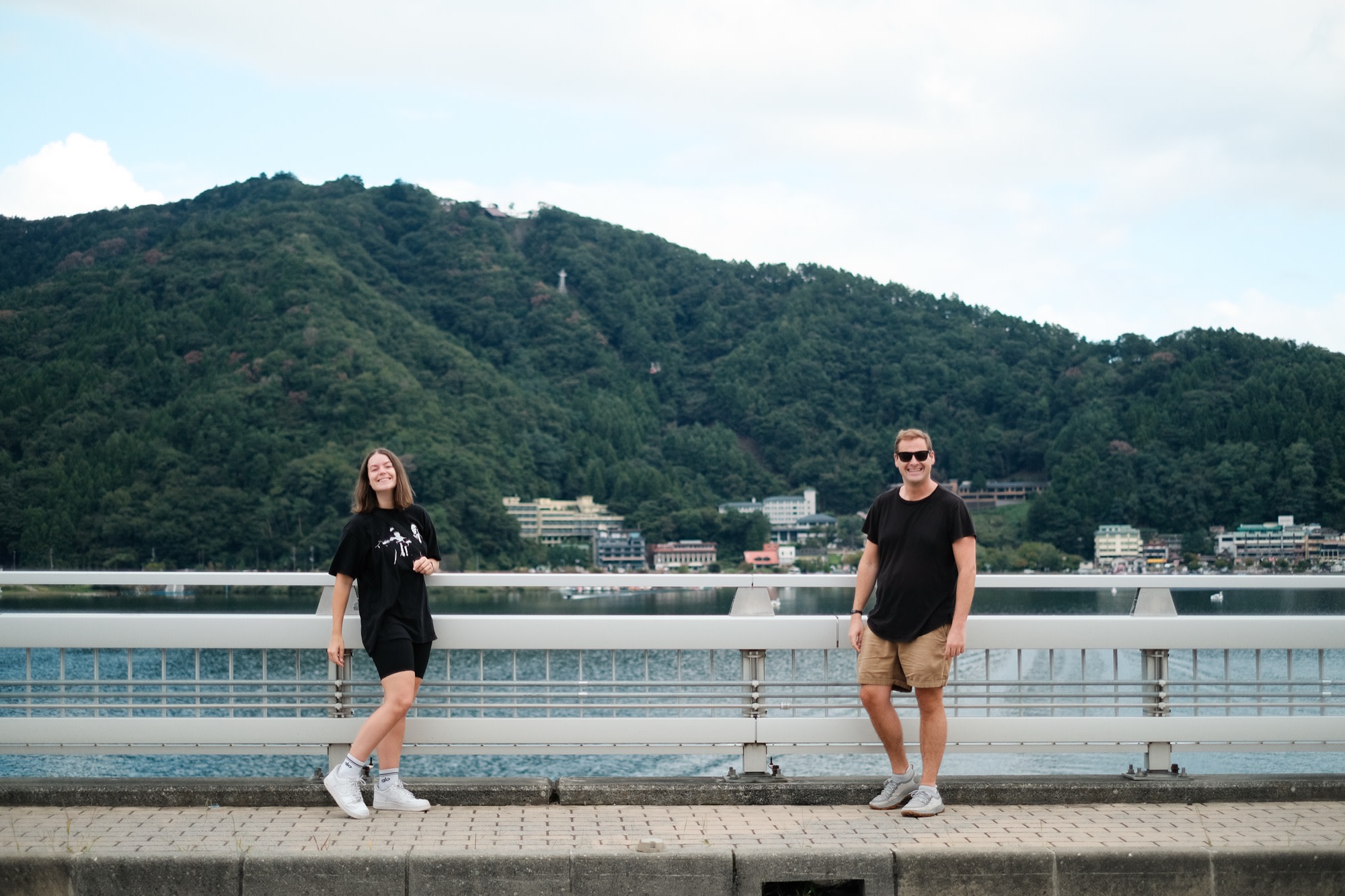 Friends on a bridge below a mountain lake