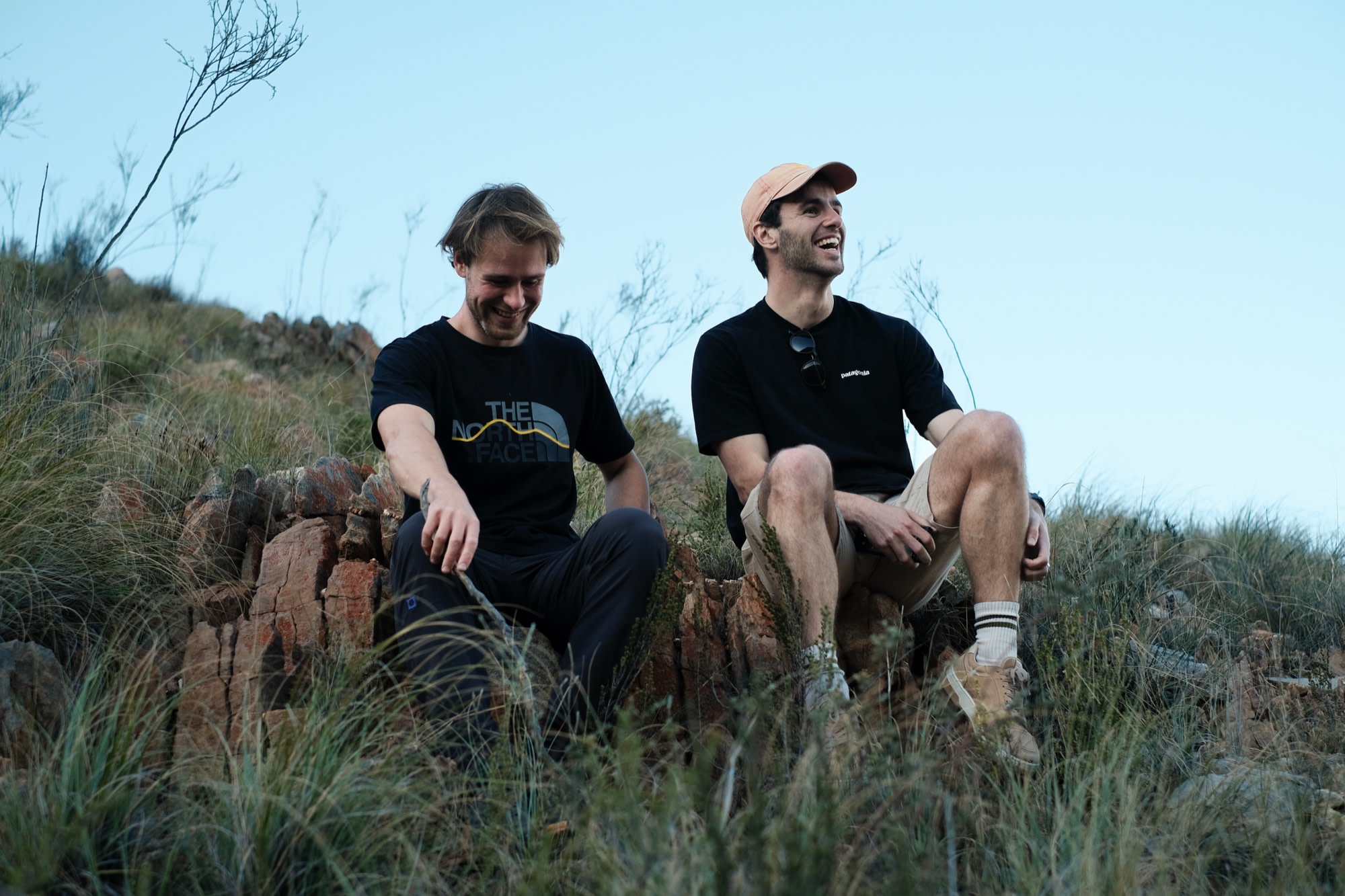 Two friends laughing among the fynbos at dusk
