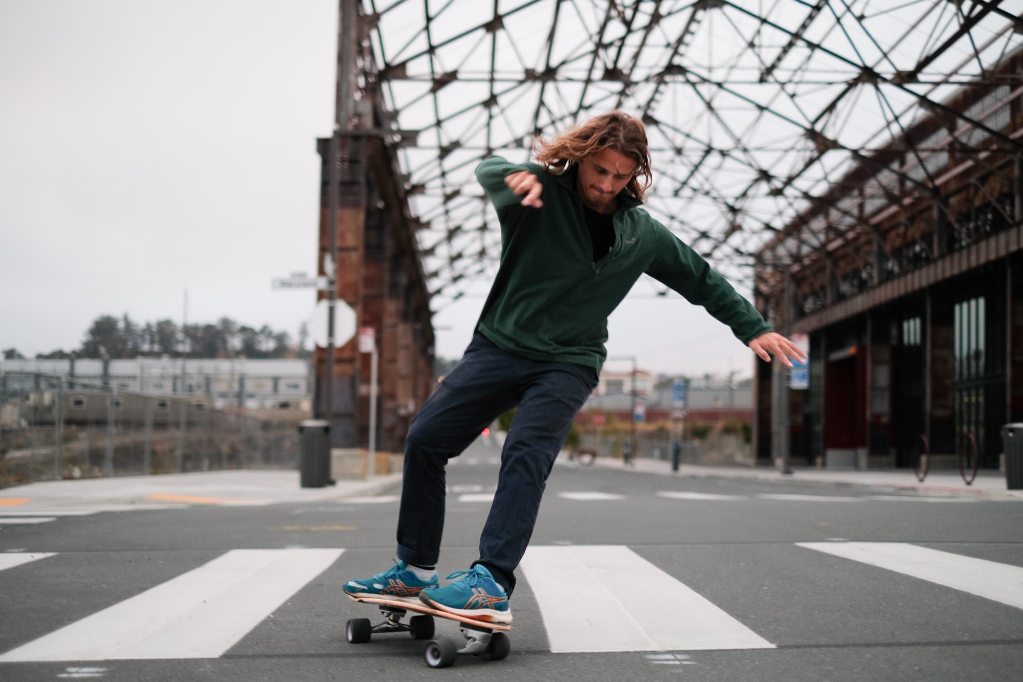 Laurence carving on his skateboard under an old pier shed