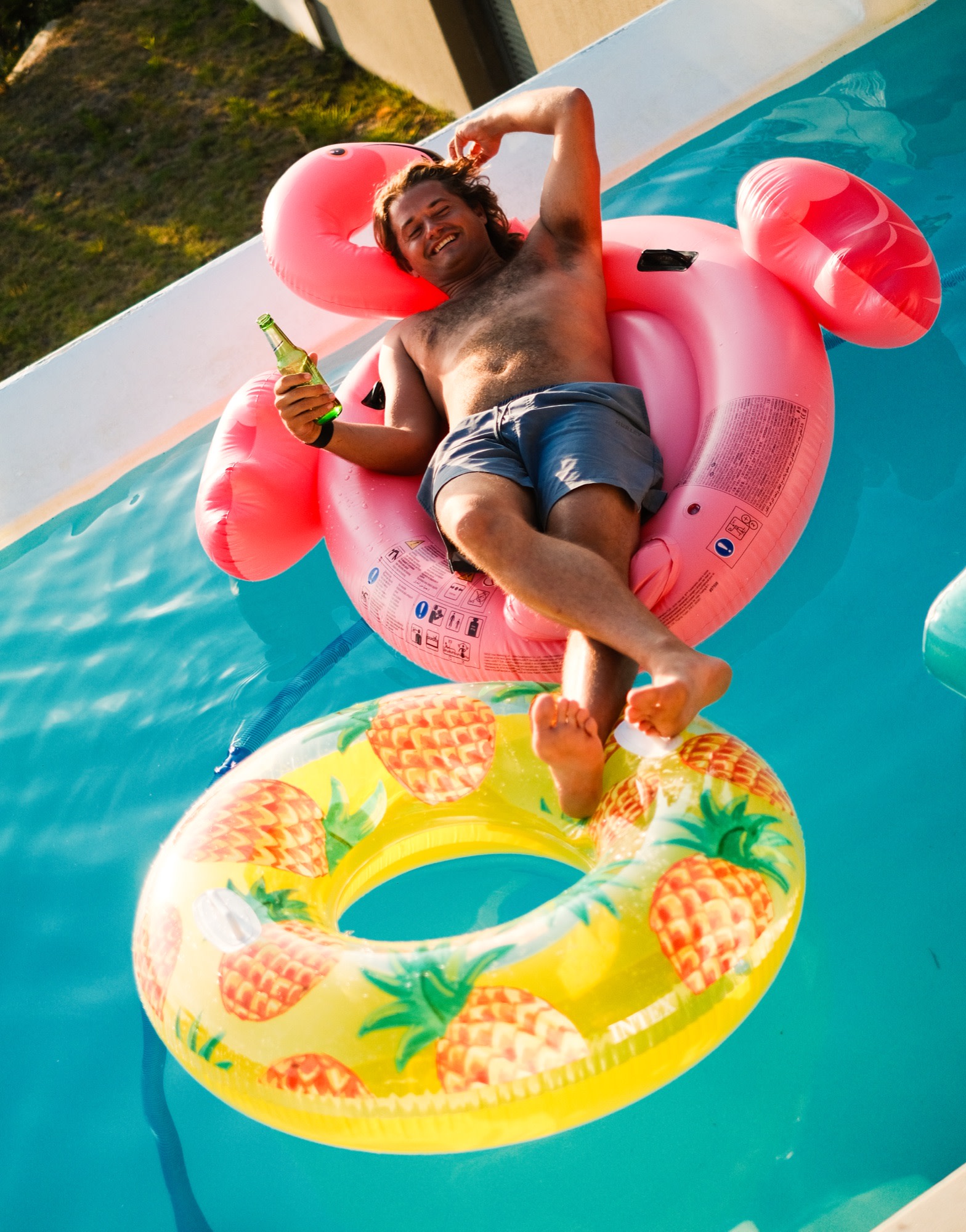 Laurence lounging on a flamingo float with a beer