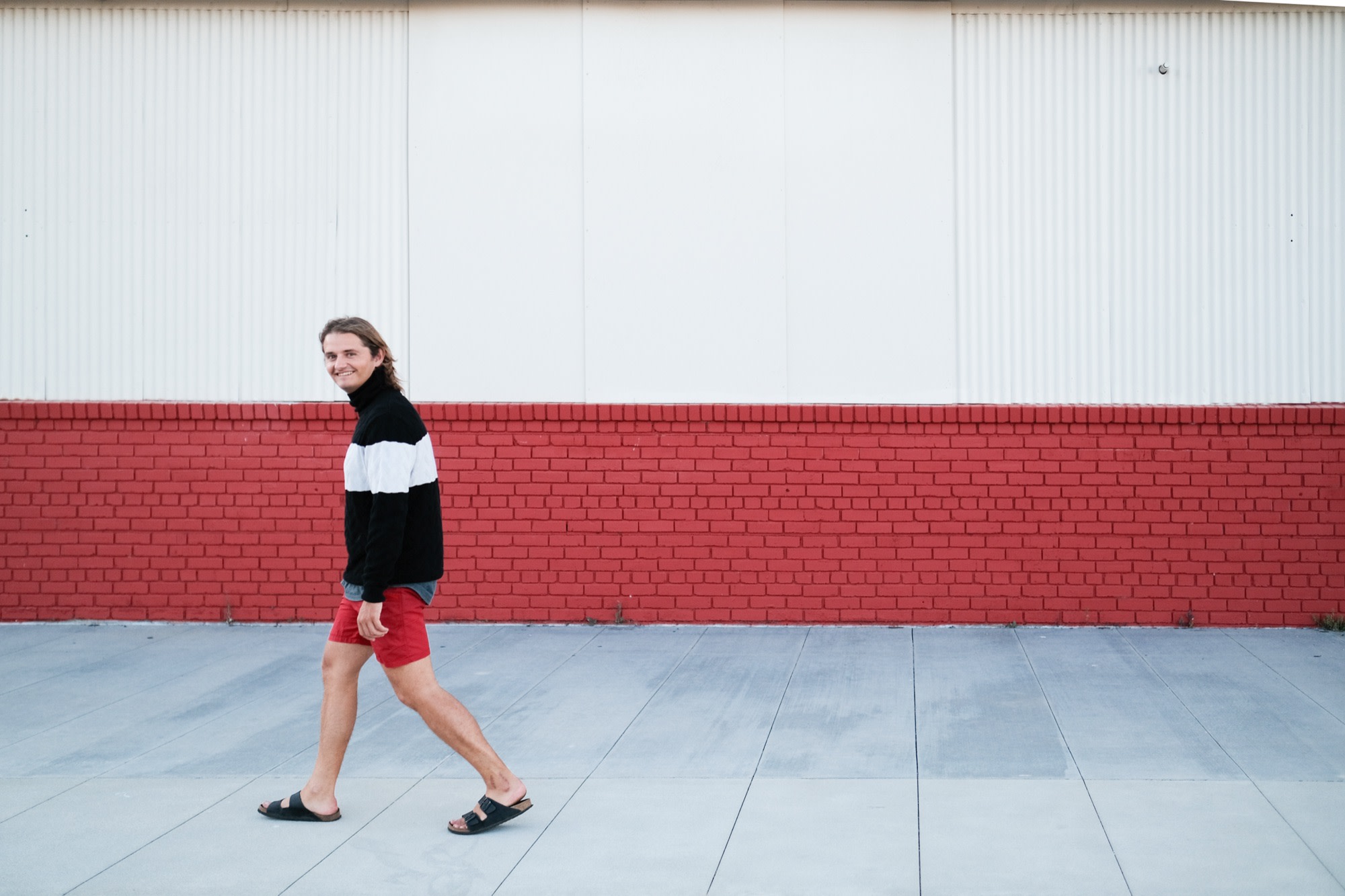 Laurence walking past a red-and-white wall