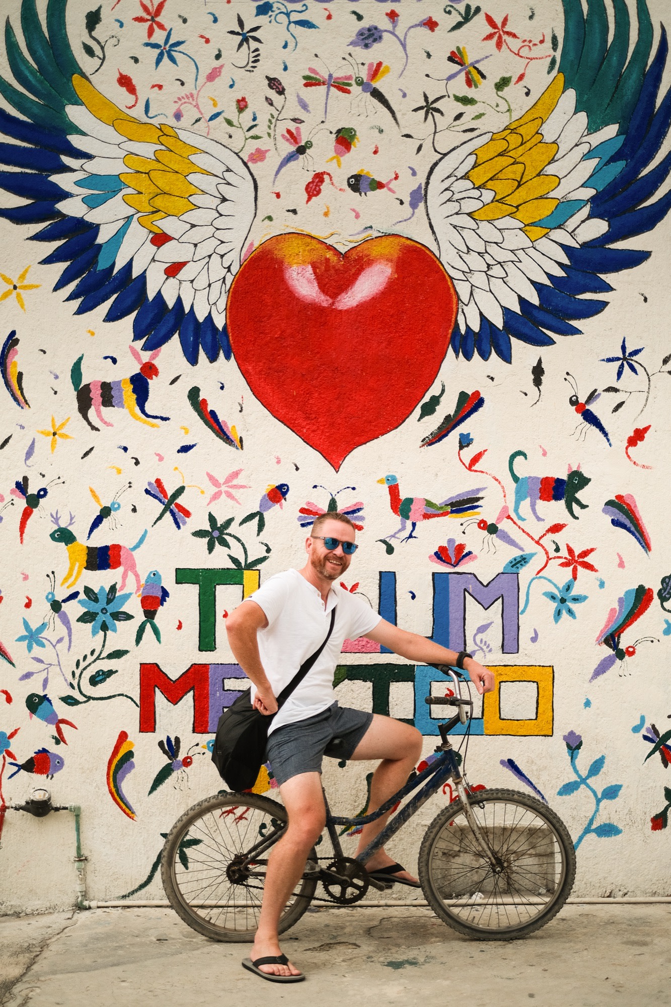 On a bike in front of a winged-heart mural