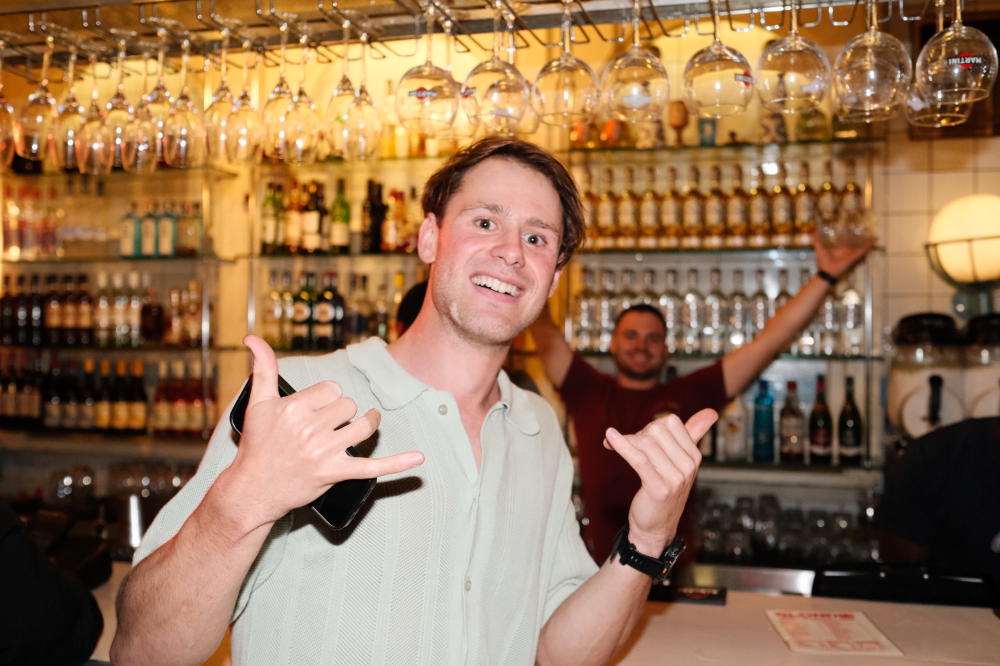Double shakas at the bar under a rack of hanging glasses
