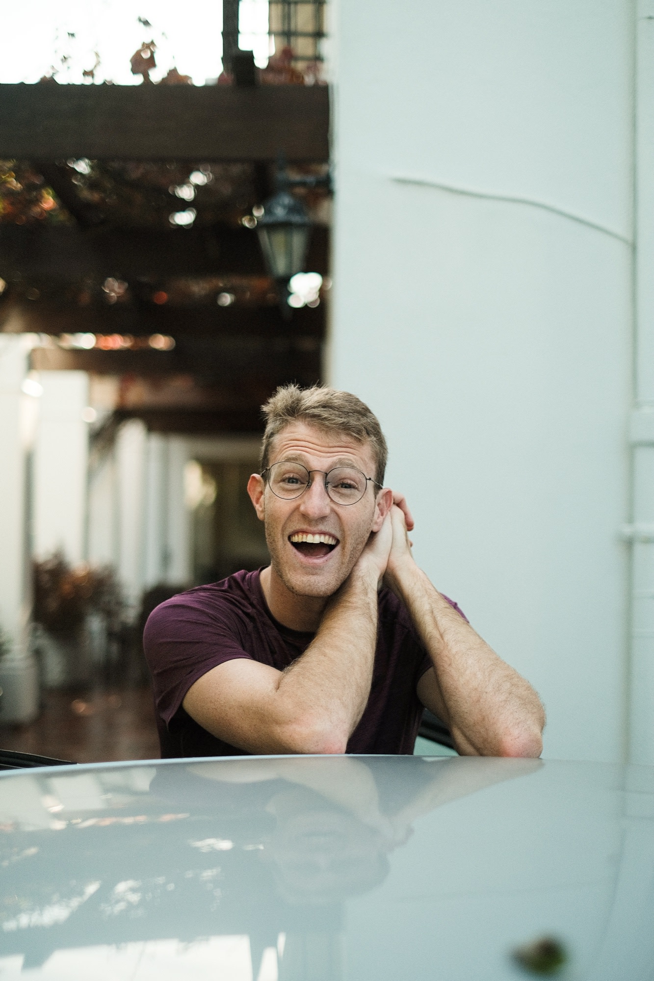 A big open-mouthed laugh, chin resting on a car roof