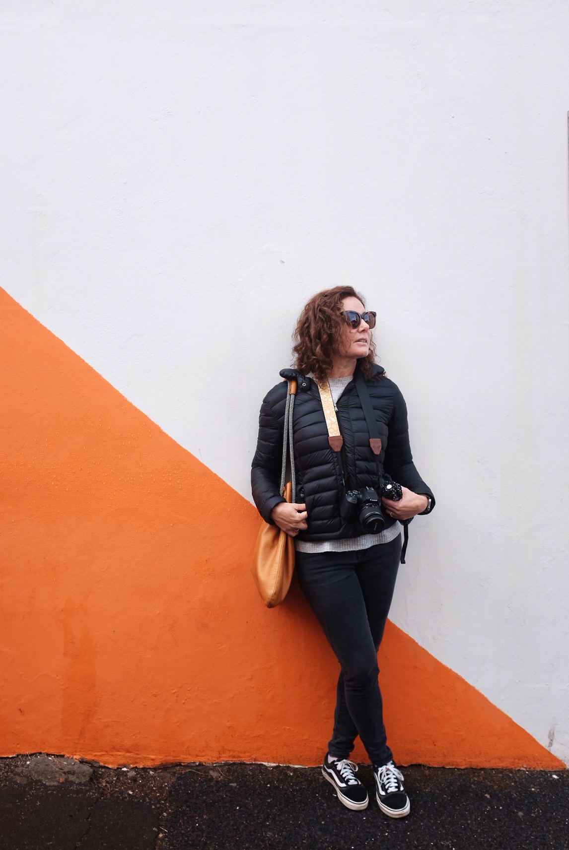 Leaning on an orange-and-white wall, cameras in hand