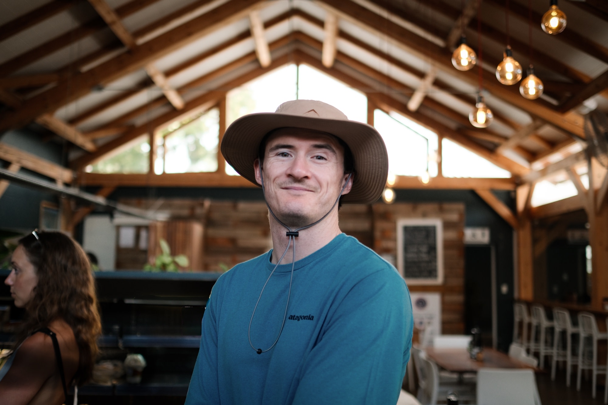 Under the timber rafters in a bucket hat and tee
