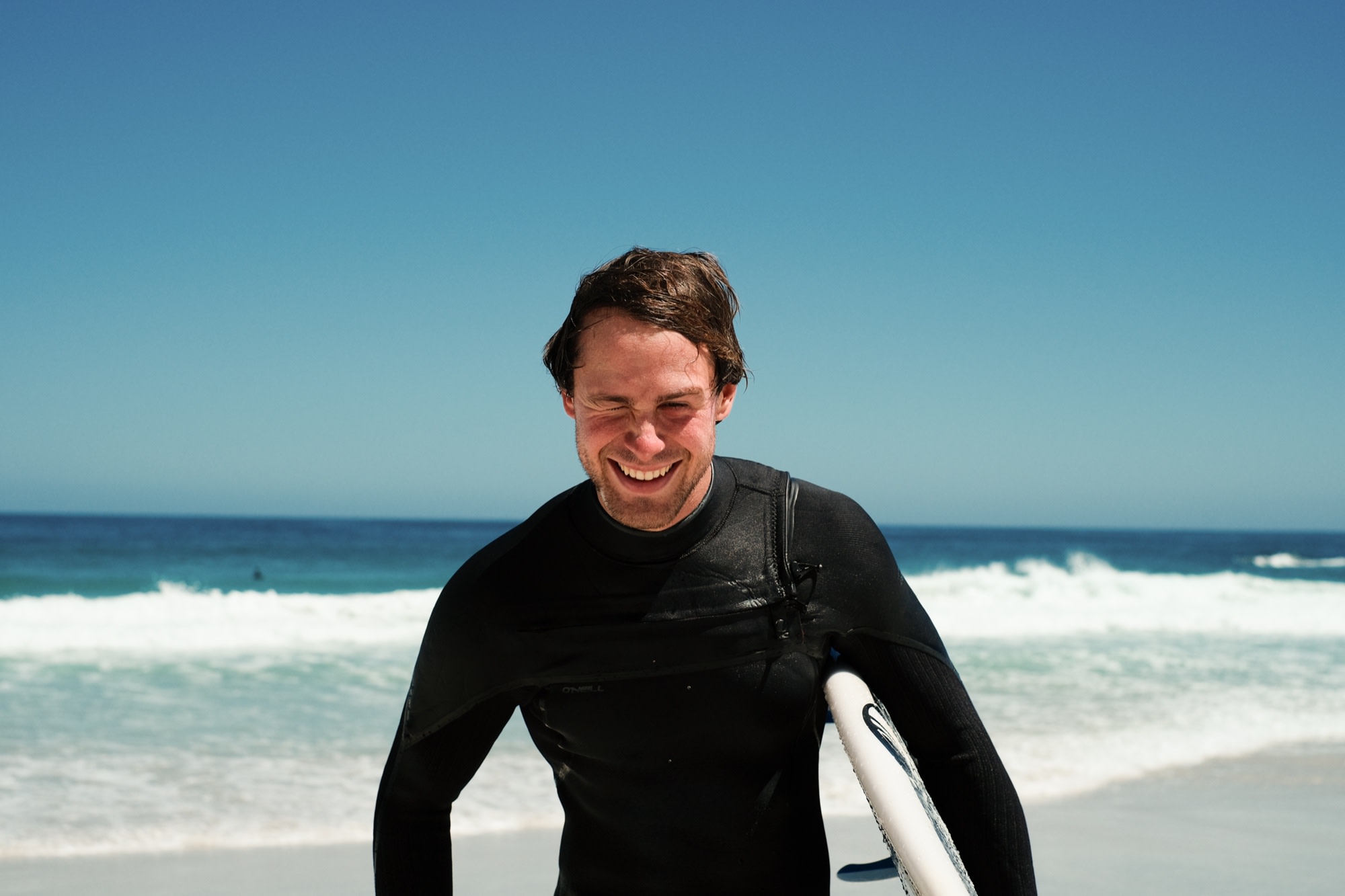 A sun-squinting laugh coming out of the surf