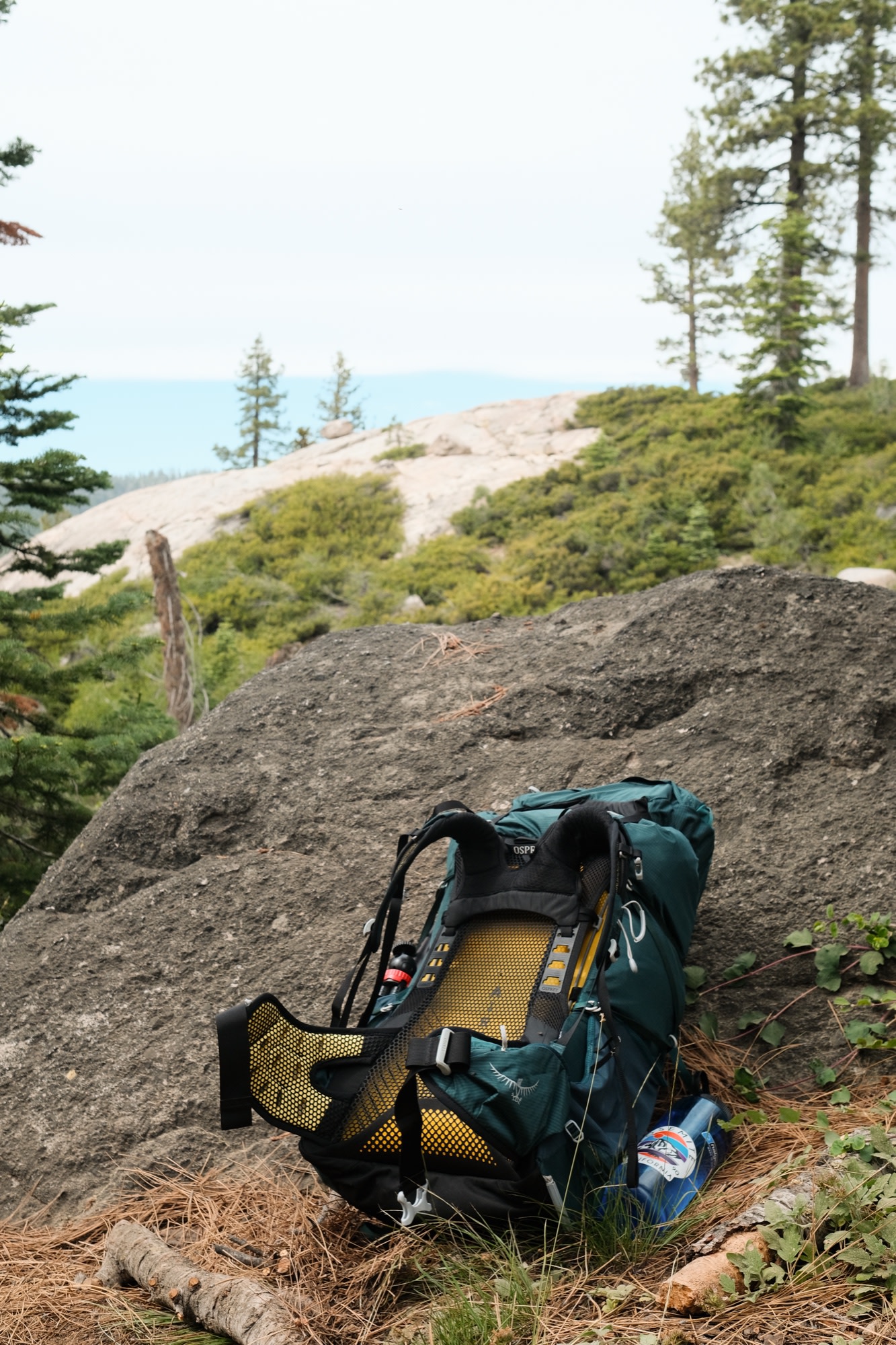 An Osprey pack resting against a granite boulder