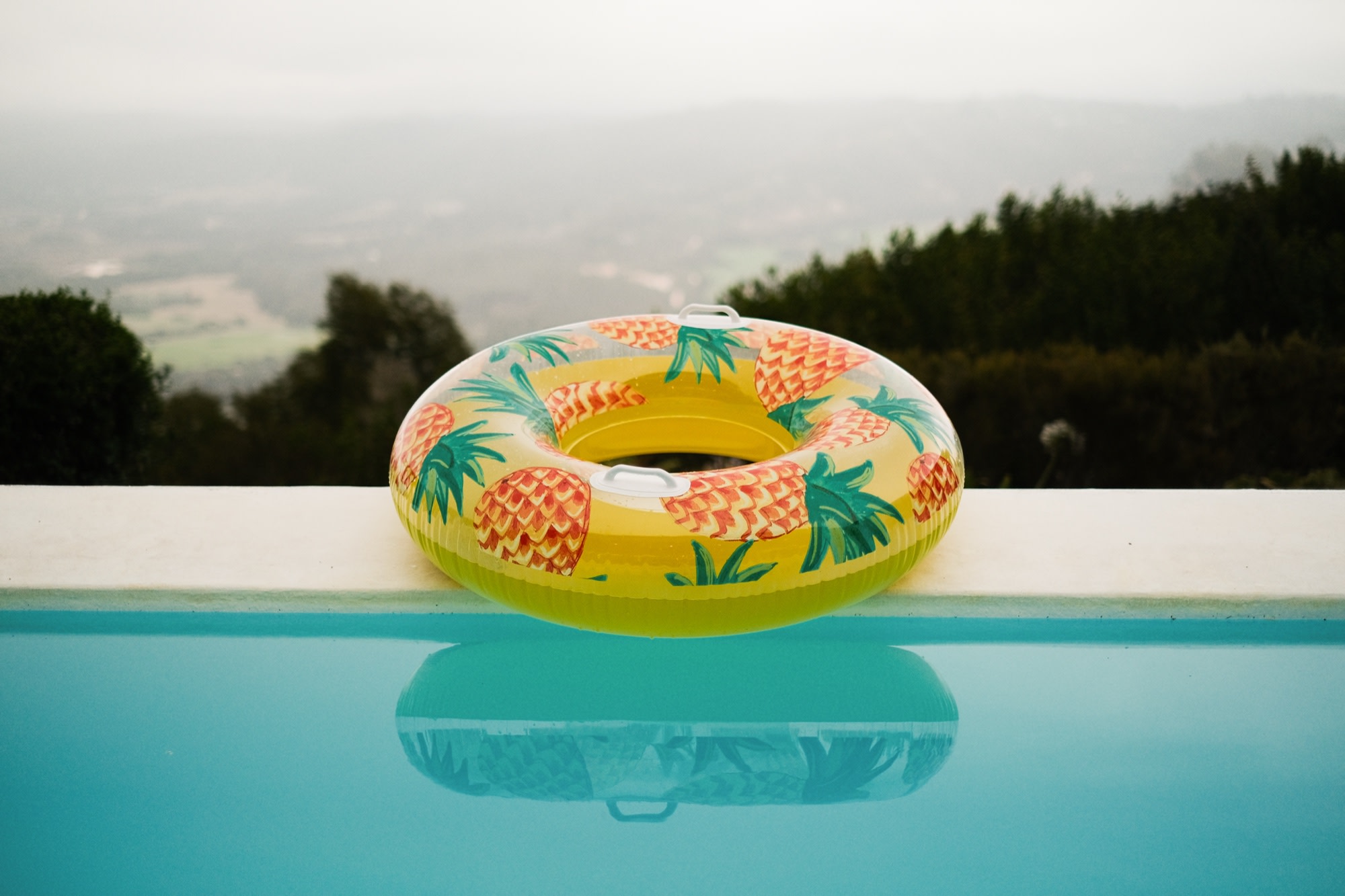 A pineapple pool float above a hazy valley
