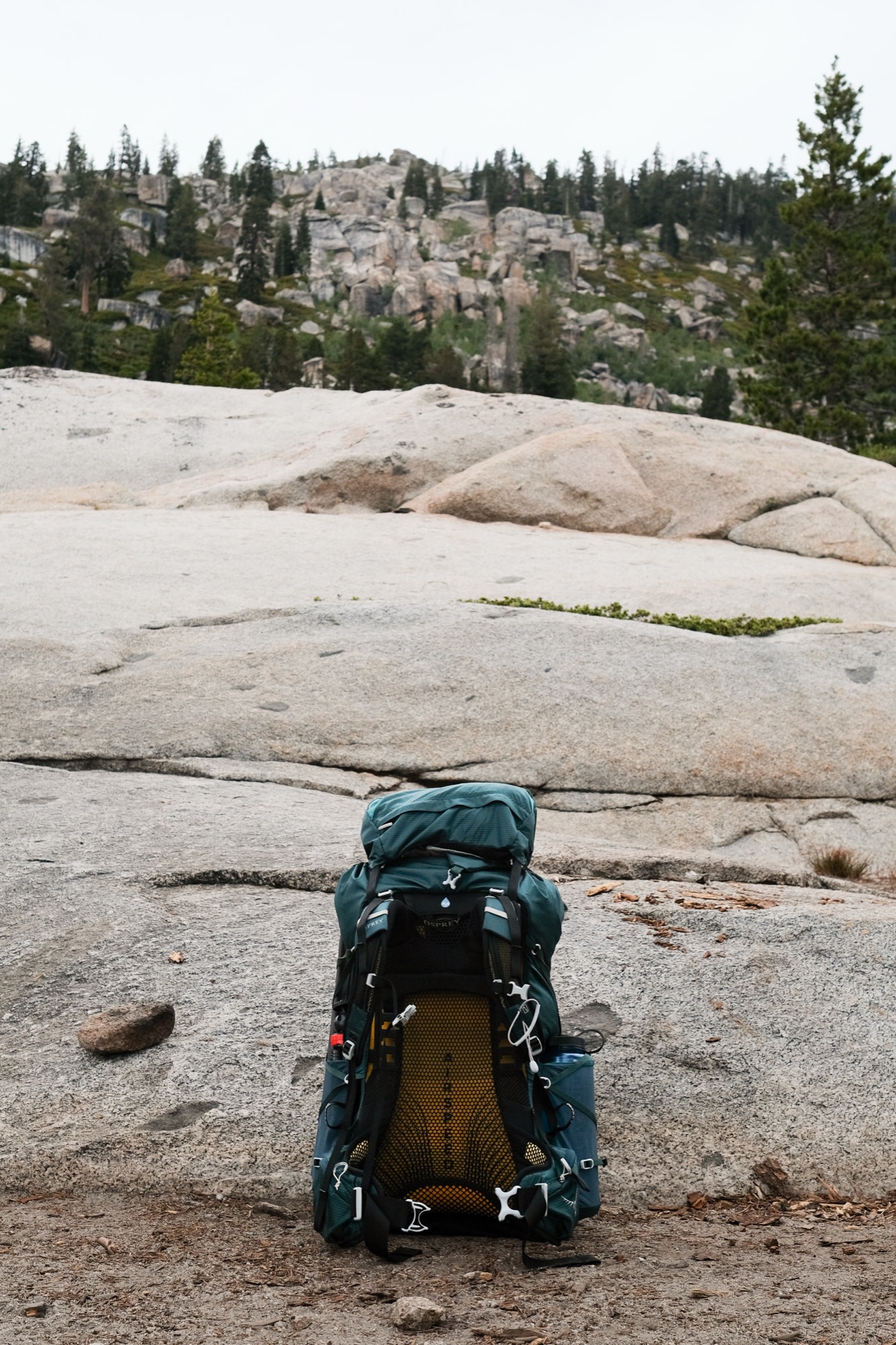 An Osprey pack on the granite, mountains beyond
