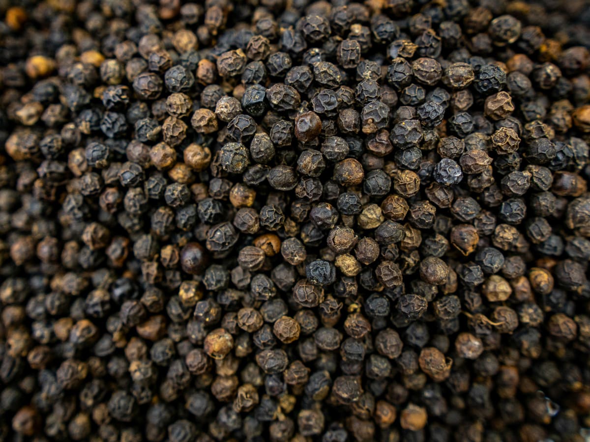 Close-up of dried black peppercorns showing their dark textured surfaces.