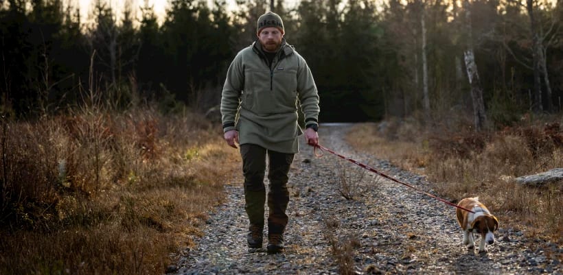 Jeger med hund på skogsvei i Swazi-klær