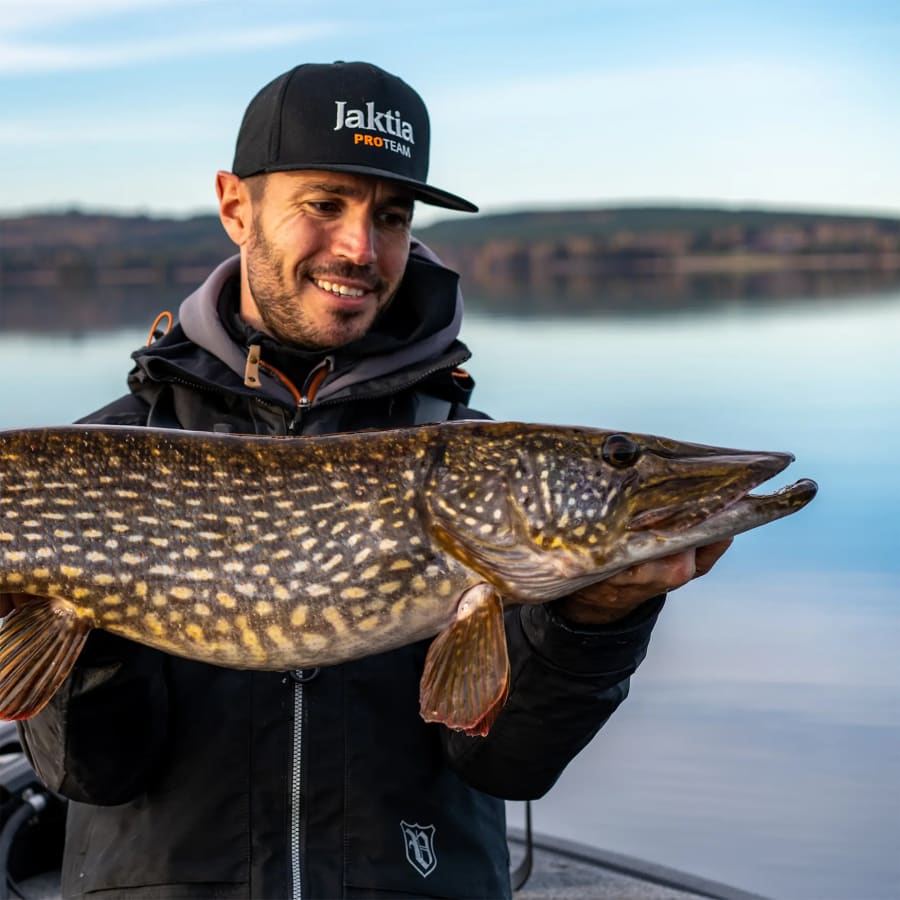 Fisker med en stor gjedde ved vannet